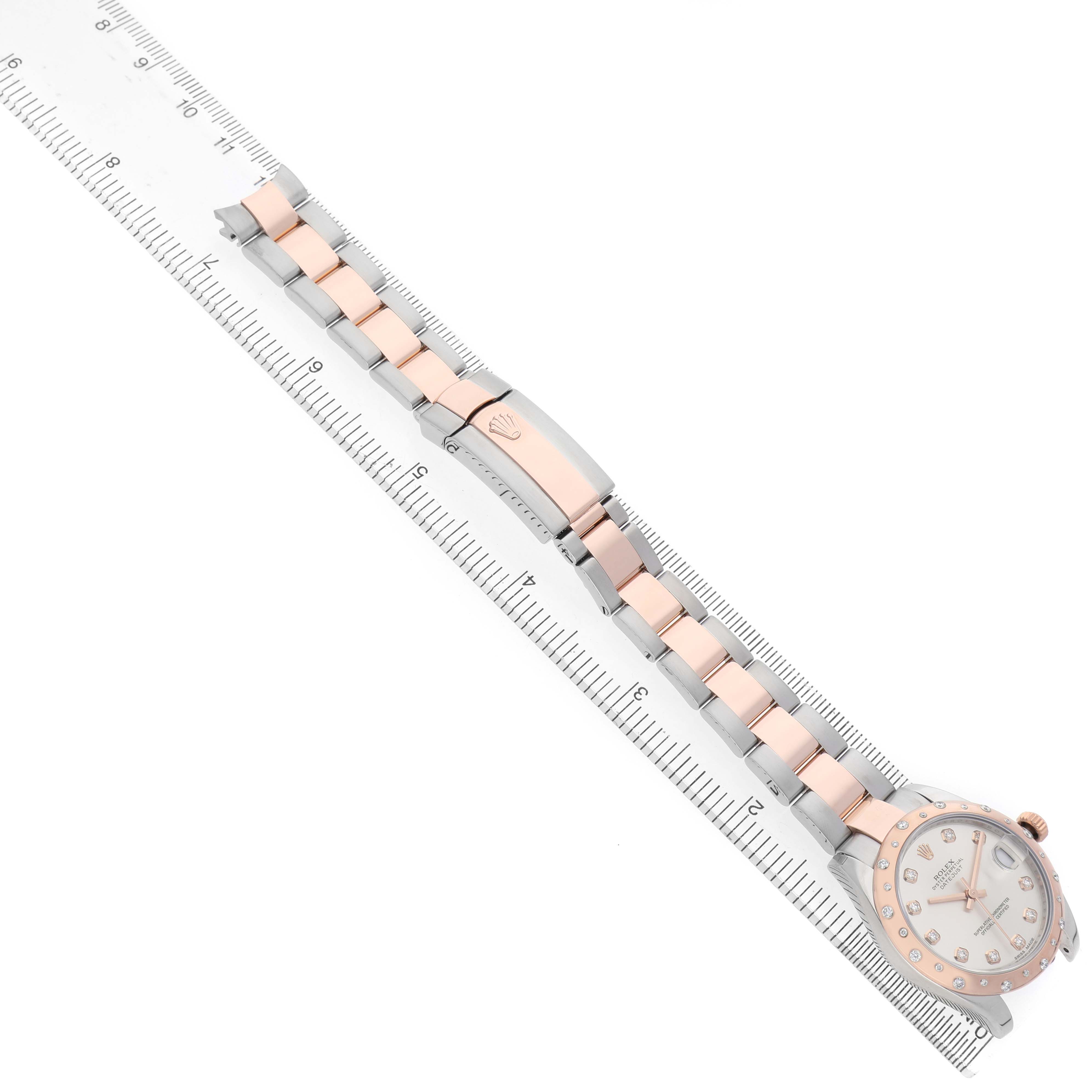 The image shows a Rolex Datejust 178341 Women's Steel and Gold (two tone) Silver Dial watch laid flat with the face and full bracelet, alongside a ruler for scale.