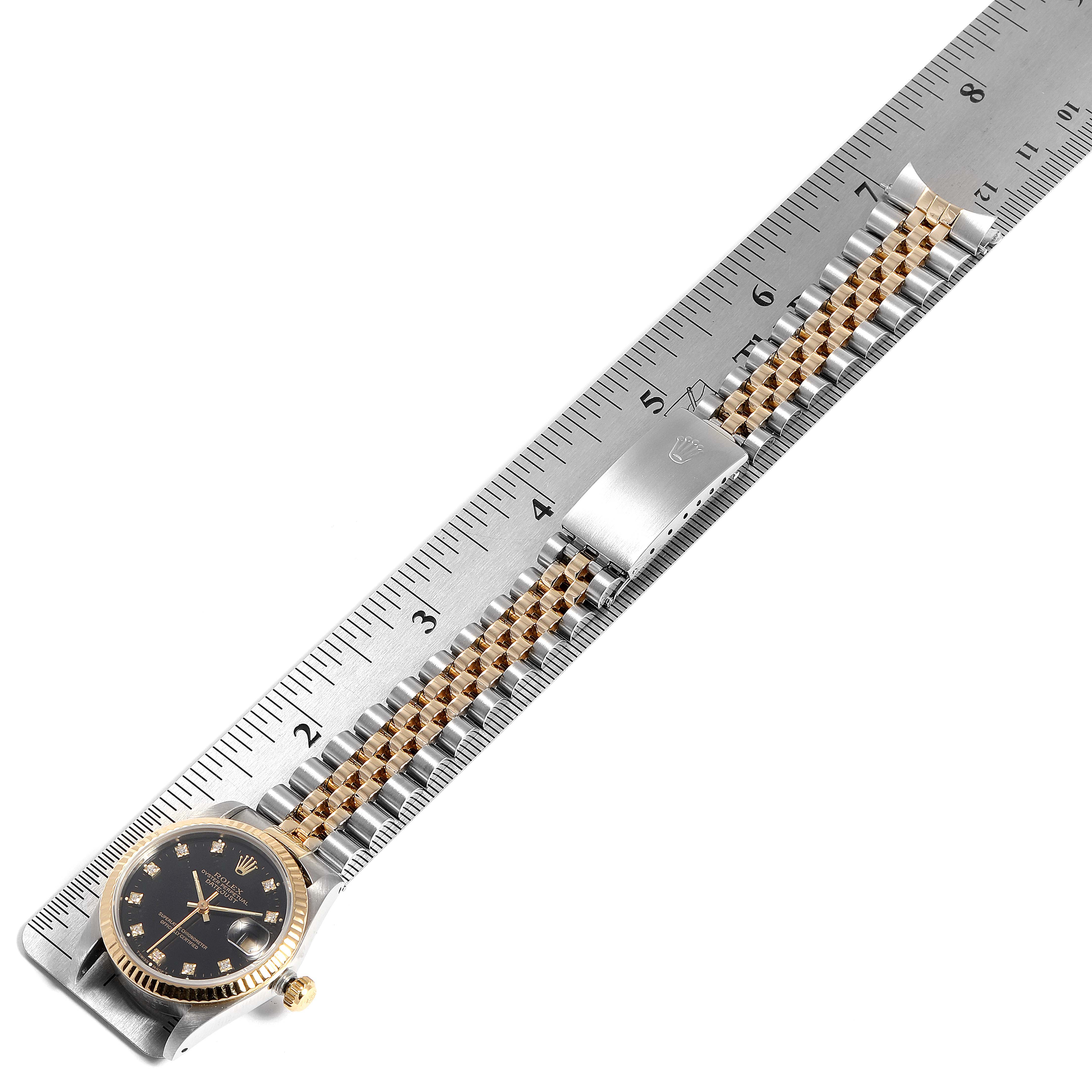The Rolex Mid-Size 68273 Women
s Steel and Gold (two tone) Black Dial 68273 Women
s Steel and Gold (two tone) Black Dial watch is shown fully extended alongside a ruler, displaying its face, bezel, bracelet, and clasp.