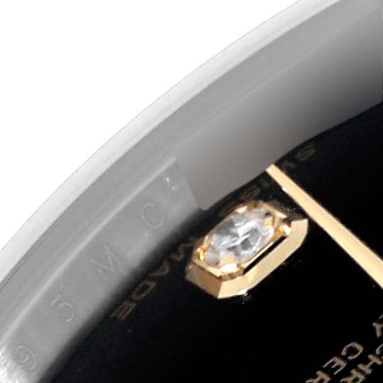 This close-up image of a Rolex Mid-Size 178273 Women's Steel and Gold (two tone) Black Dial 178273 Women's Steel and Gold (two tone) Black Dial watch shows part of the bezel, a diamond hour marker, and a portion of the dial.