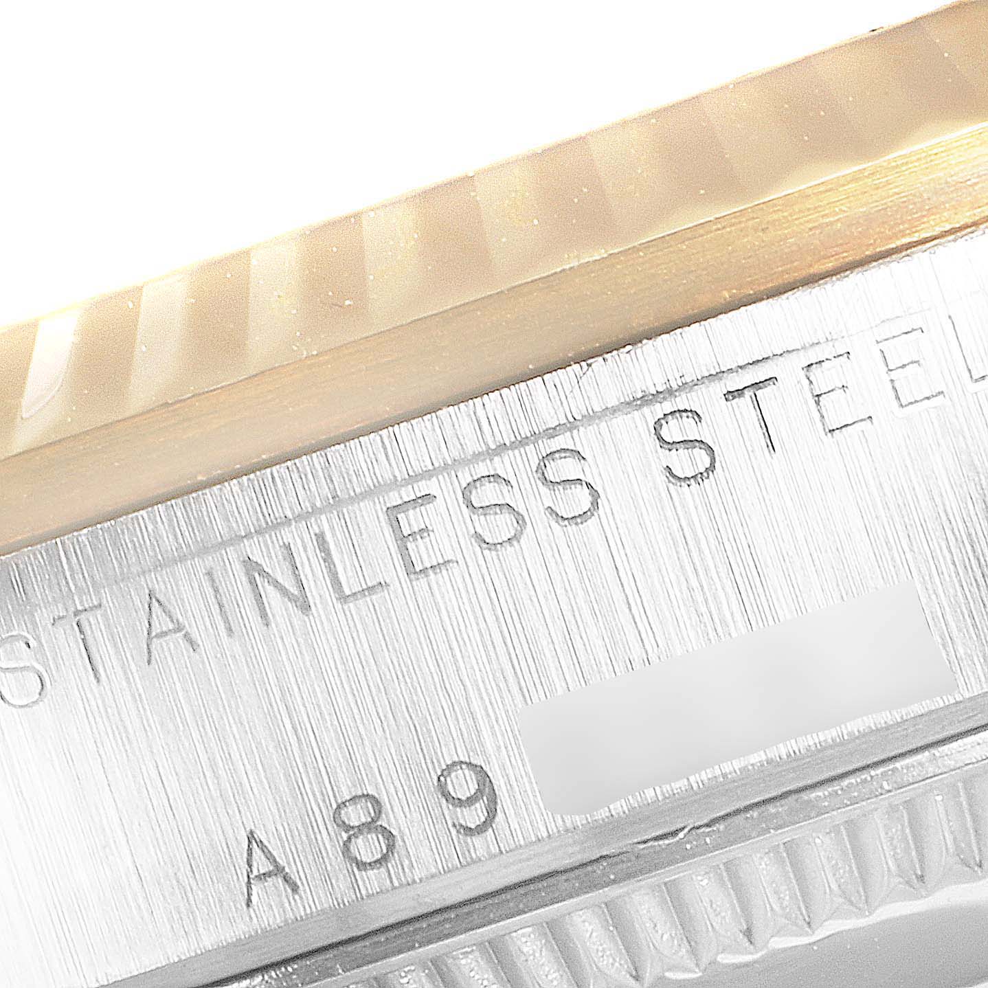 This close-up image of a Rolex Mid-Size 78273 Women
s Steel and Gold (two tone) White Dial 78273 Women
s Steel and Gold (two tone) White Dial watch shows the engraving on its stainless steel casing near the bezel.