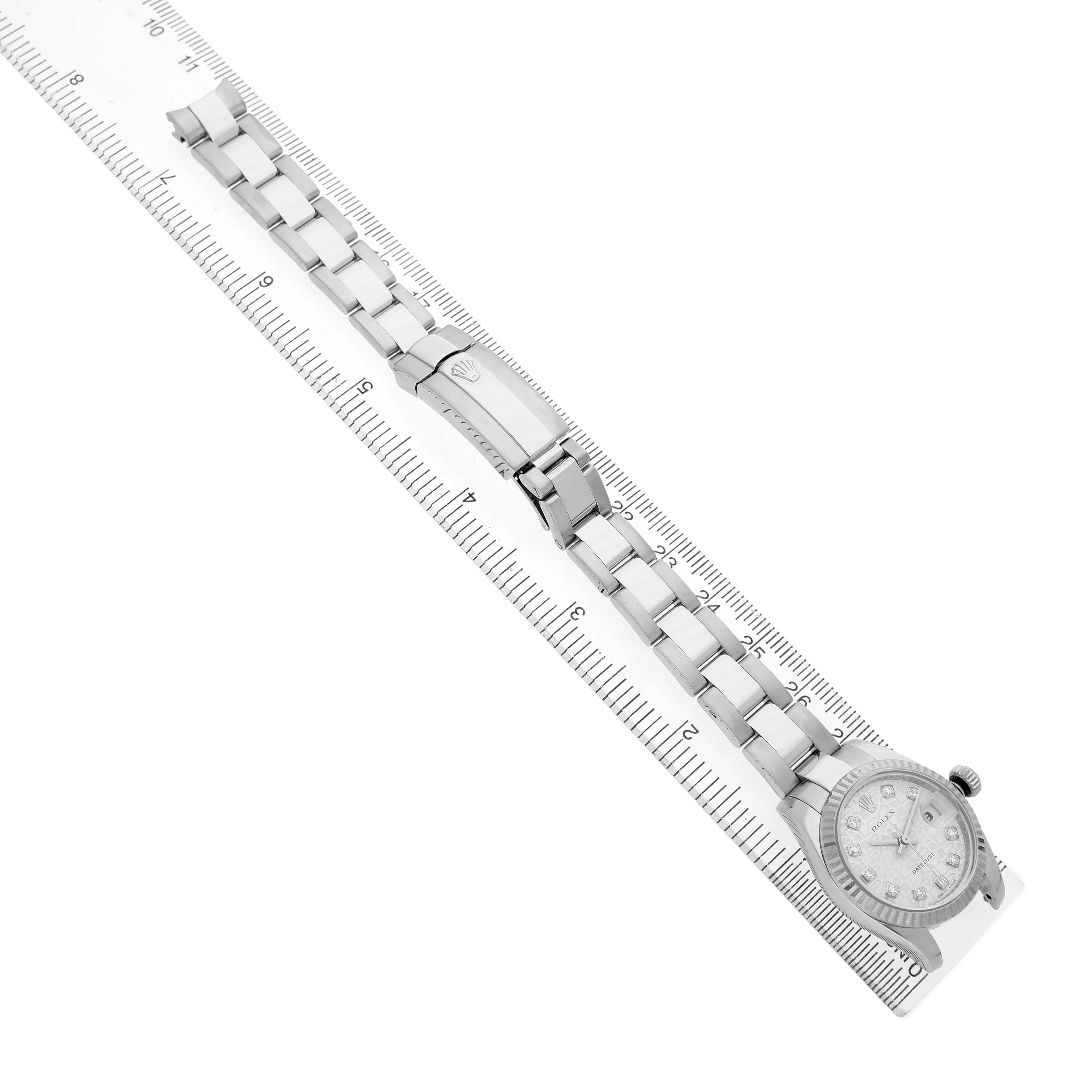 The Rolex Datejust 179174 Women's Stainless Steel Silver Dial watch is shown from a top angle, displaying the full length of the bracelet alongside a ruler.
