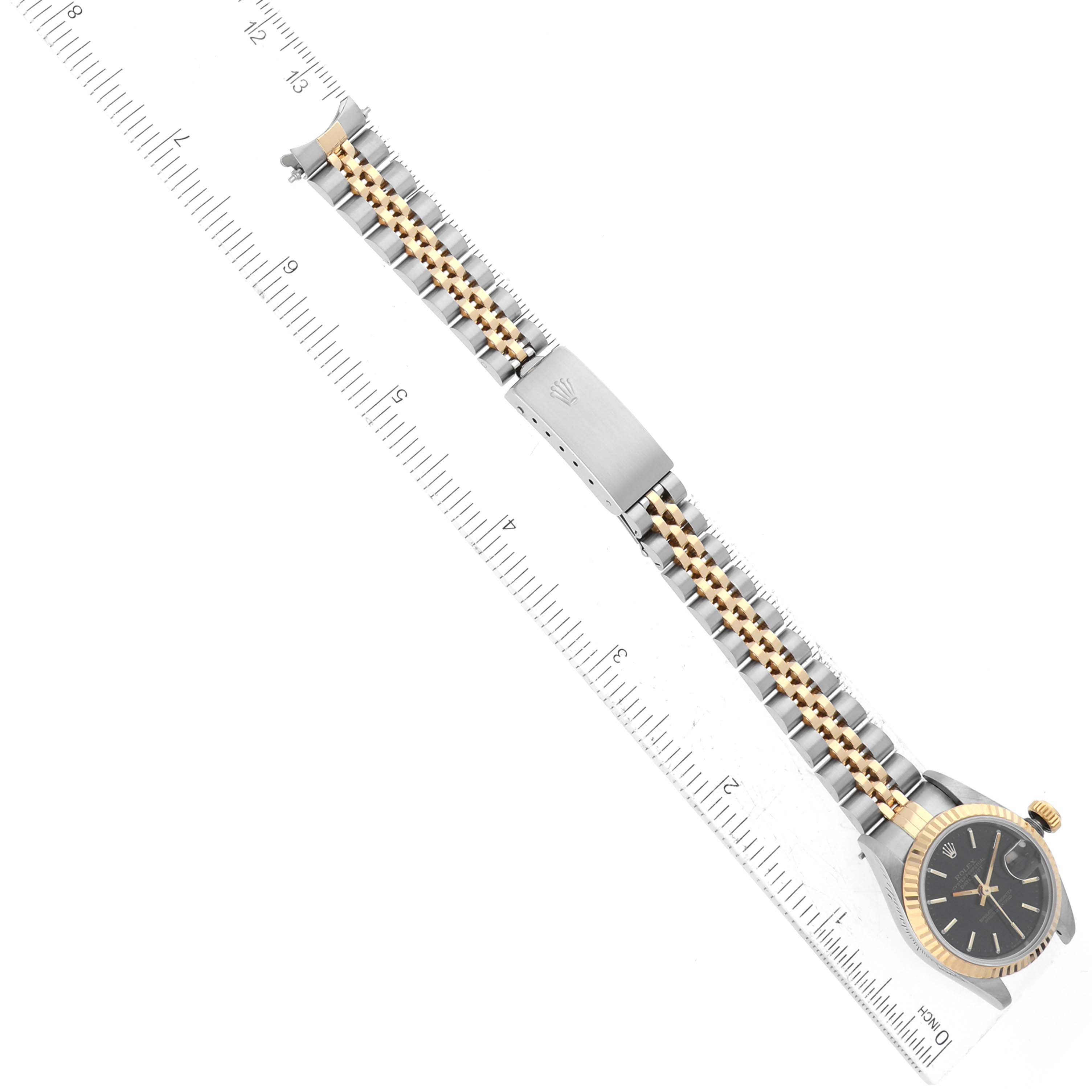 This image shows the Rolex Datejust 69173 Women's Steel and Gold (two tone) Black Dial 69173 Women's Steel and Gold (two tone) Black Dial watch from a top-down angle, displaying its band and clasp alongside a measuring ruler.