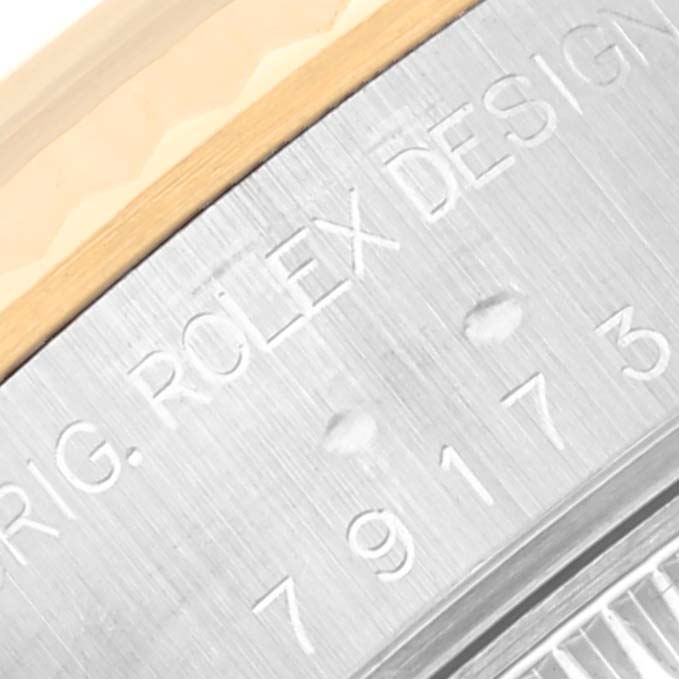 The image shows a close-up view of the edge of a Rolex Datejust 79173 Women's Steel and Gold (two tone) Silver Dial 79173 Women's Steel and Gold (two tone) Silver Dial watch, highlighting the engraved bezel and serial number.