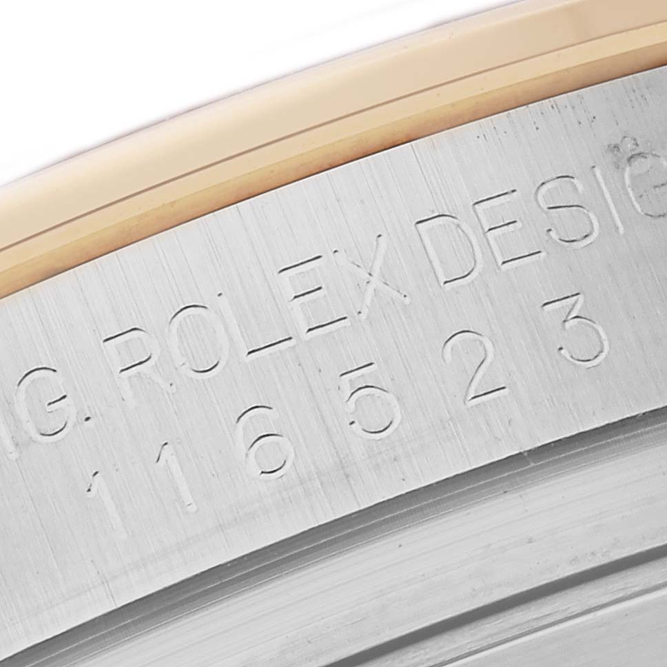 The image shows a close-up of the engraved serial number on the side of a Rolex Daytona 116523 Men
s Steel and Gold (two tone) Black Dial 116523 Men
s Steel and Gold (two tone) Black Dial watch case.