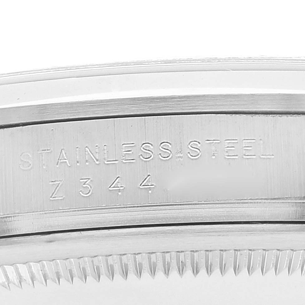 This close-up image shows the side of the Rolex Explorer 114270 Men's Stainless Steel Black Dial 114270 Men's Stainless Steel Black Dial watch case with "STAINLESS STEEL" and a serial number engraved.