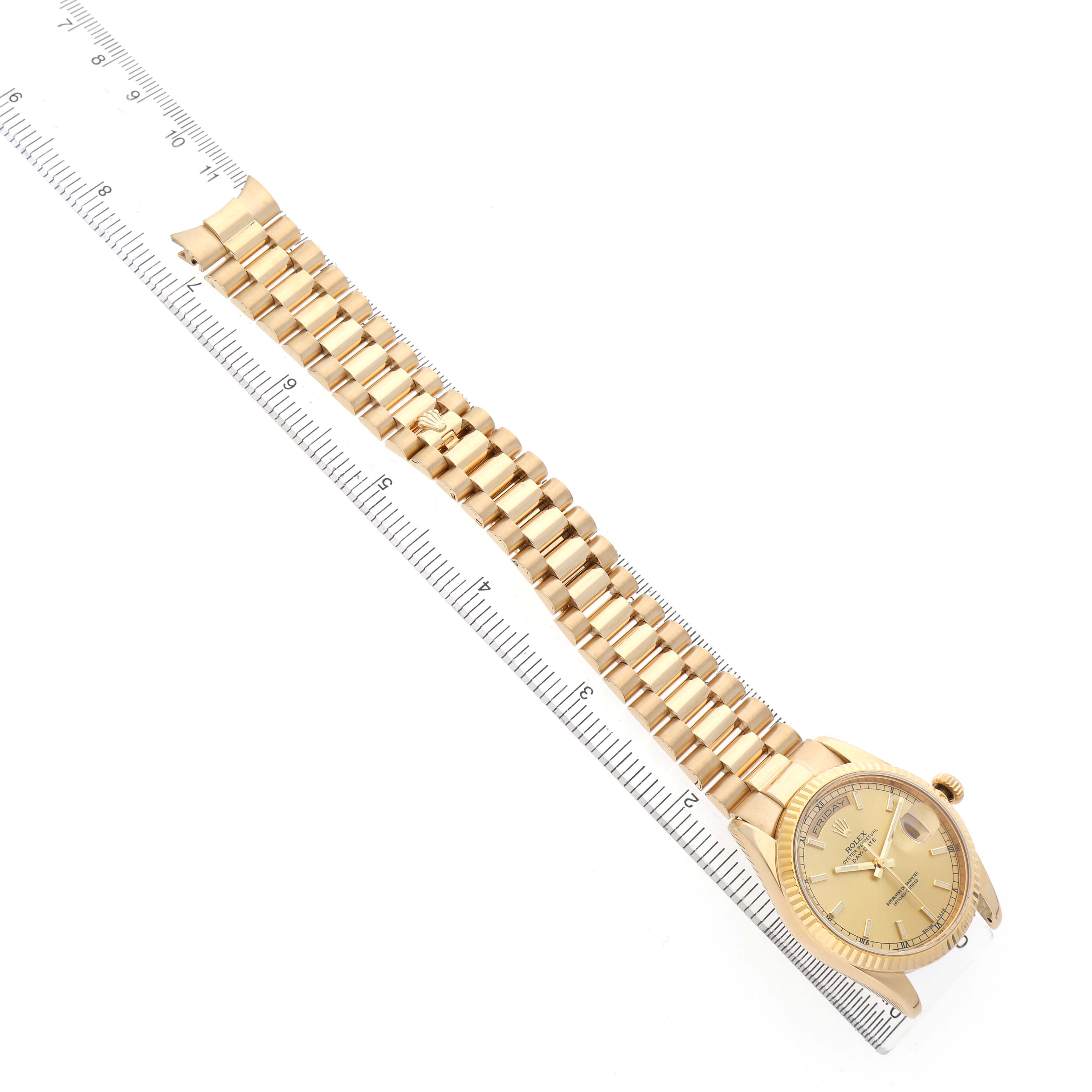 The Rolex President 118238 Men's Yellow Gold Champagne Dial watch is shown from a top-down angle, highlighting the bracelet and face alongside a ruler.