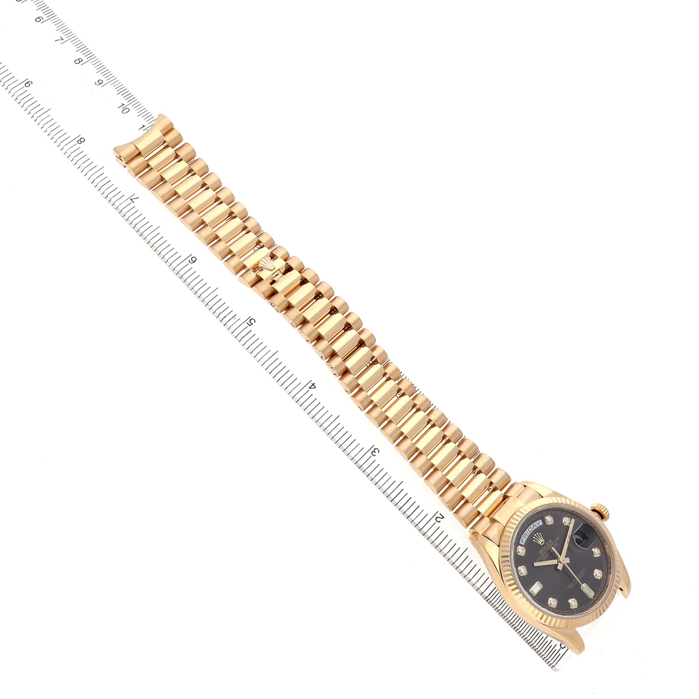 The Rolex President 128238 Men's Yellow Gold Grey Dial watch is shown from a top view, displaying the bracelet and face with a ruler beside it.