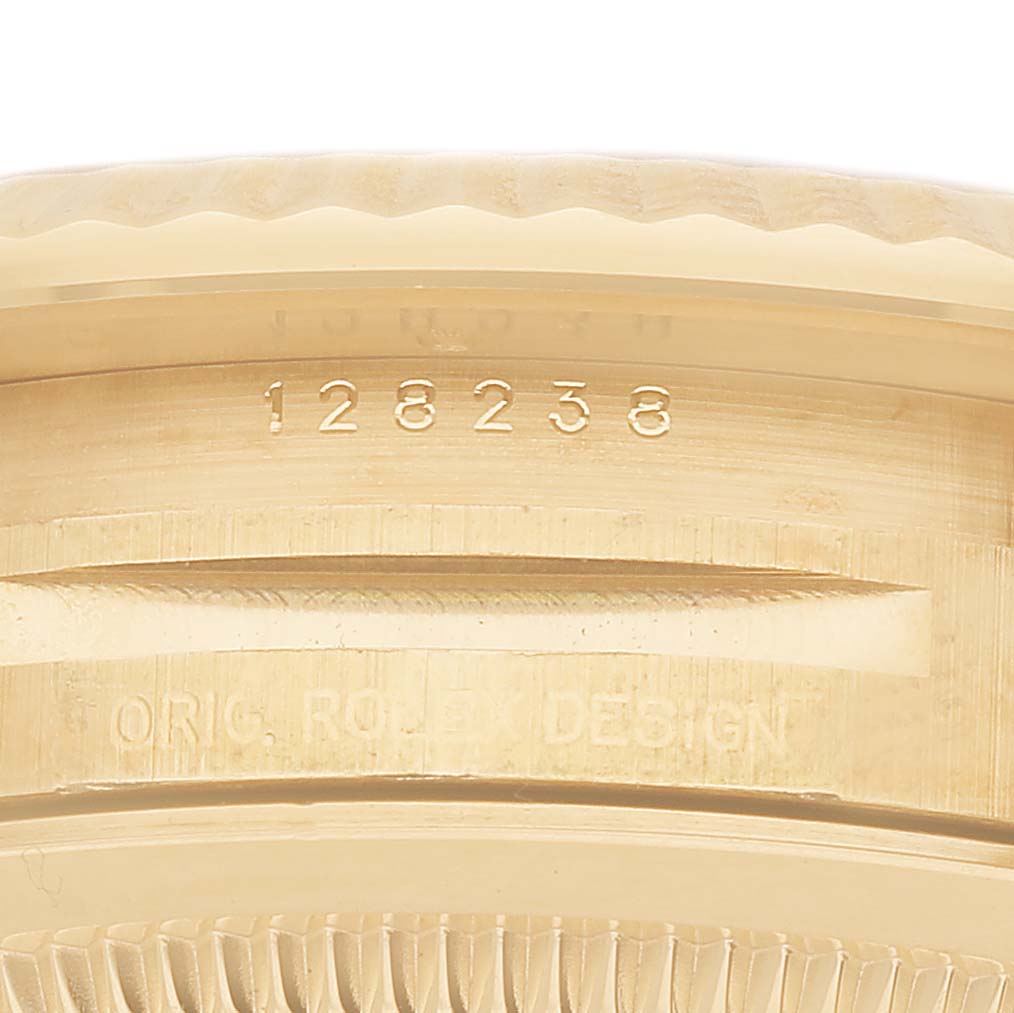 The image shows an angled close-up of the side of a Rolex President 128238 Men's Yellow Gold Grey Dial model, highlighting the engravings and fluted bezel.