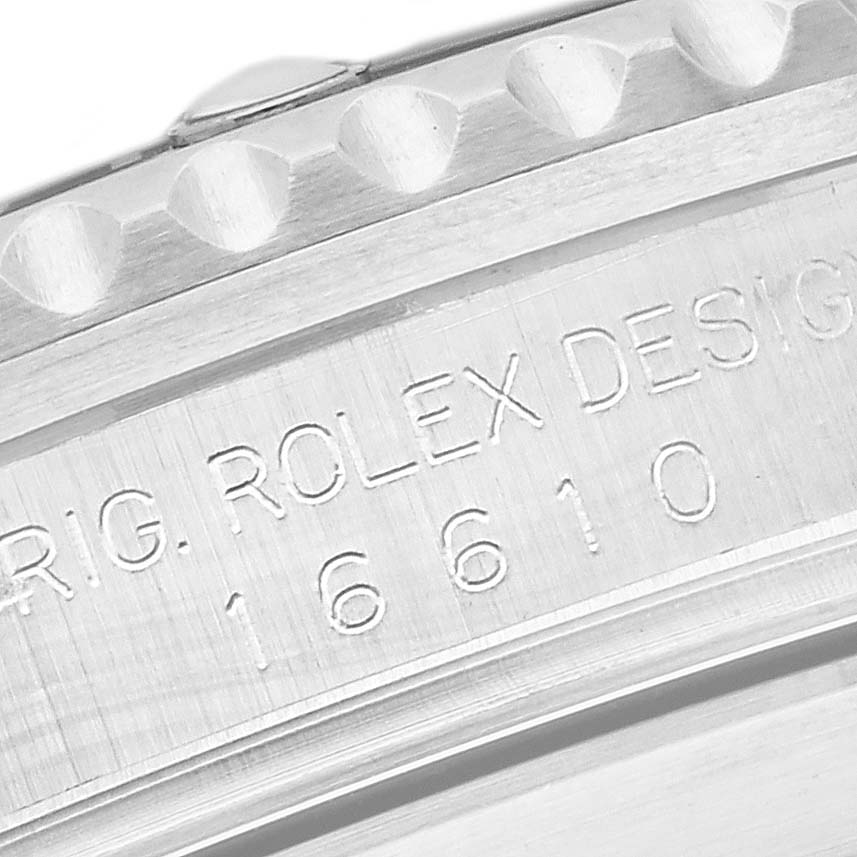 The image shows a close-up of the side profile of a Rolex Submariner 16610 Men's Stainless Steel Black Dial 16610 Men's Stainless Steel Black Dial, focusing on the engraved serial number and design text.