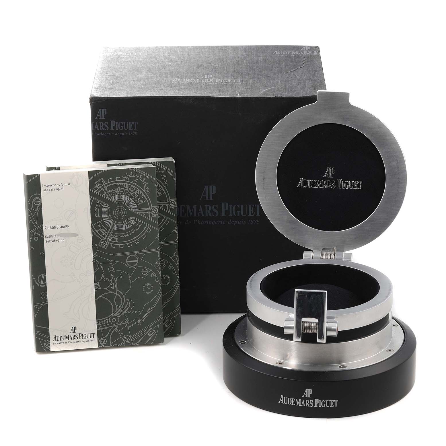 The image shows a storage box, an outer cardboard box, and a booklet for the Jules model by Audemars Piguet.