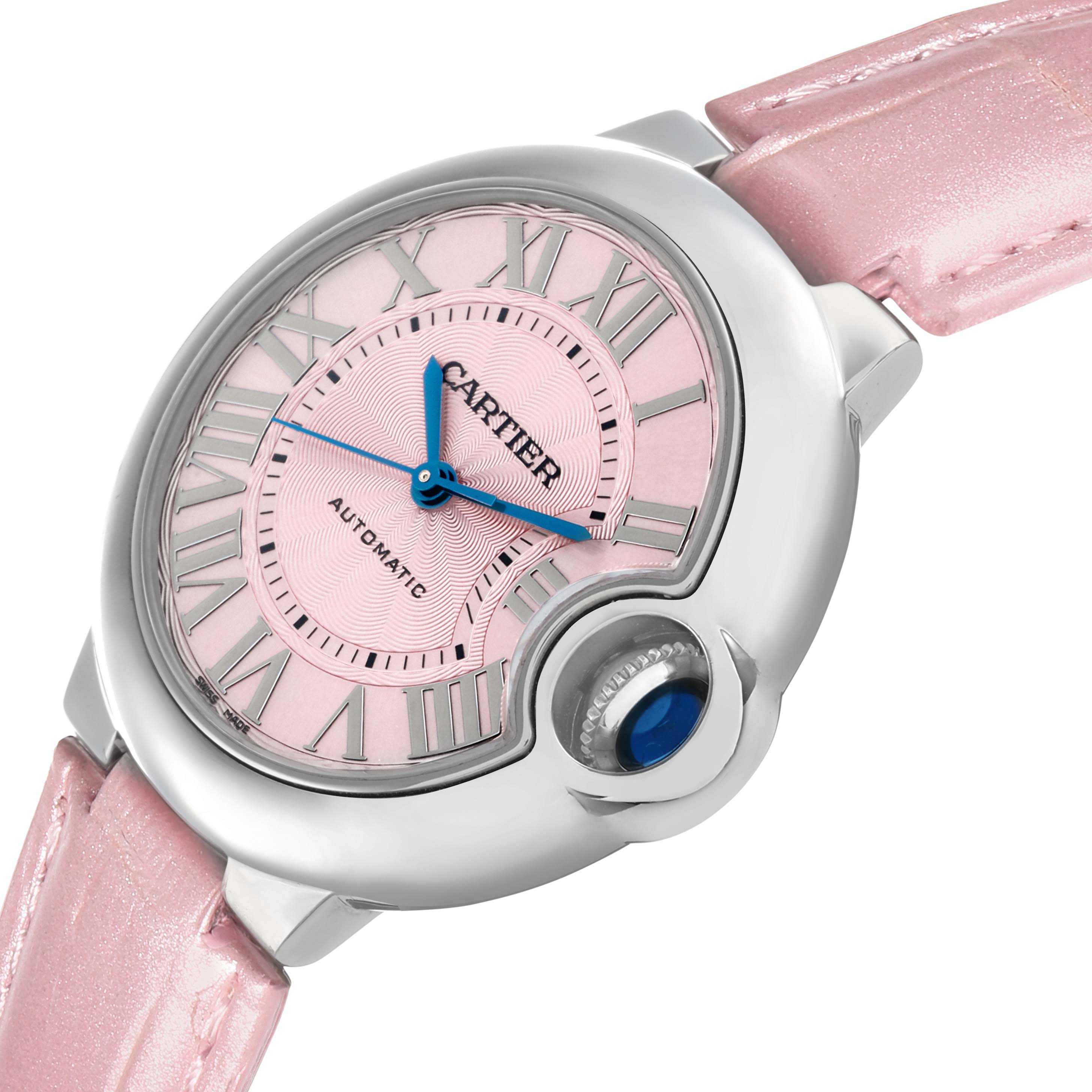 The image shows a Cartier Ballon Bleu WSBB0002 Women
s Stainless Steel Pink Dial watch with a pink dial and strap, highlighting the crown and blue hands at an angle.