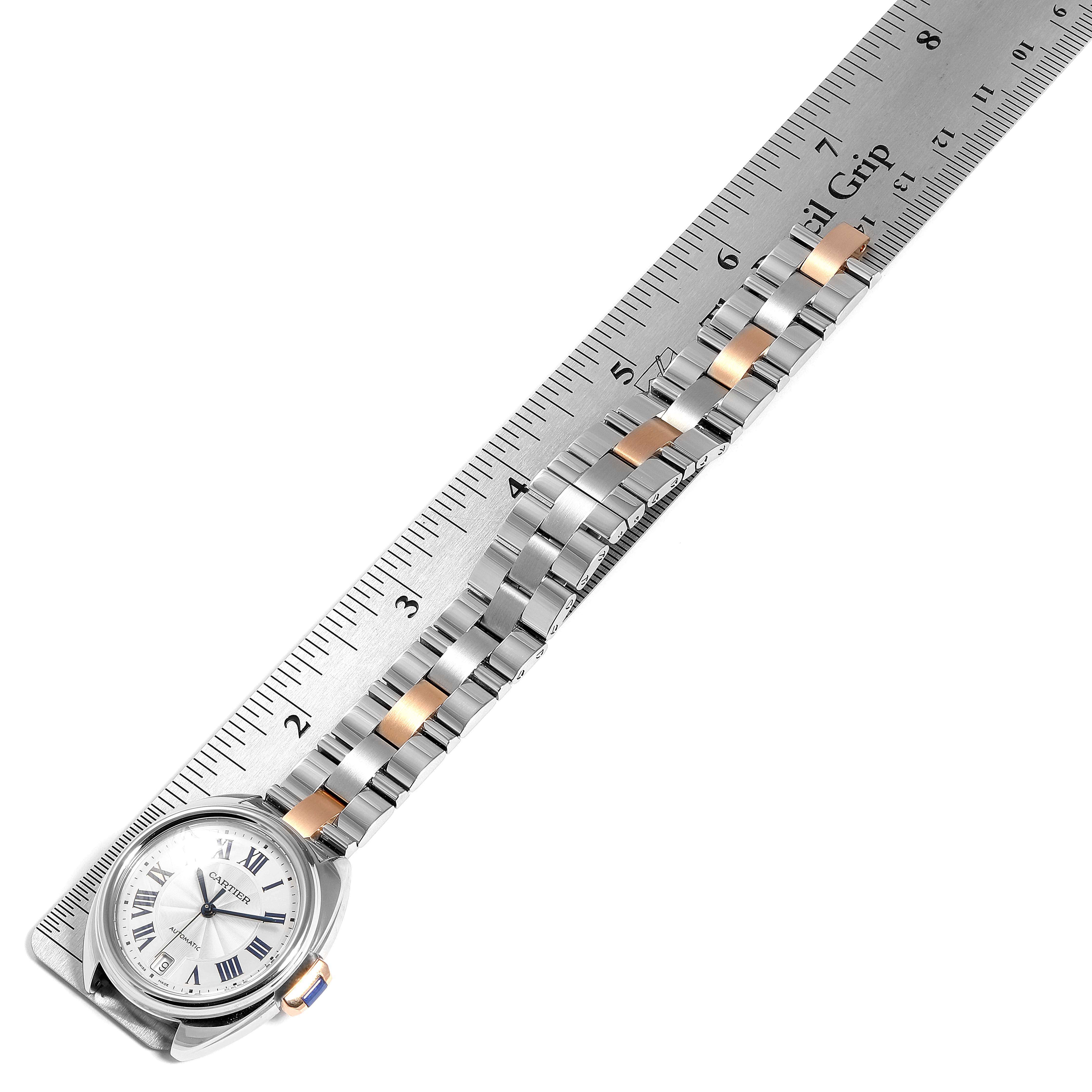The image shows a top-down view of a Cartier Cle WSCL0003 Women's Steel and Gold (two tone) Blue Dial WSCL0003 Women's Steel and Gold (two tone) Blue Dial watch placed alongside a ruler, showcasing the watch face and metal bracelet.