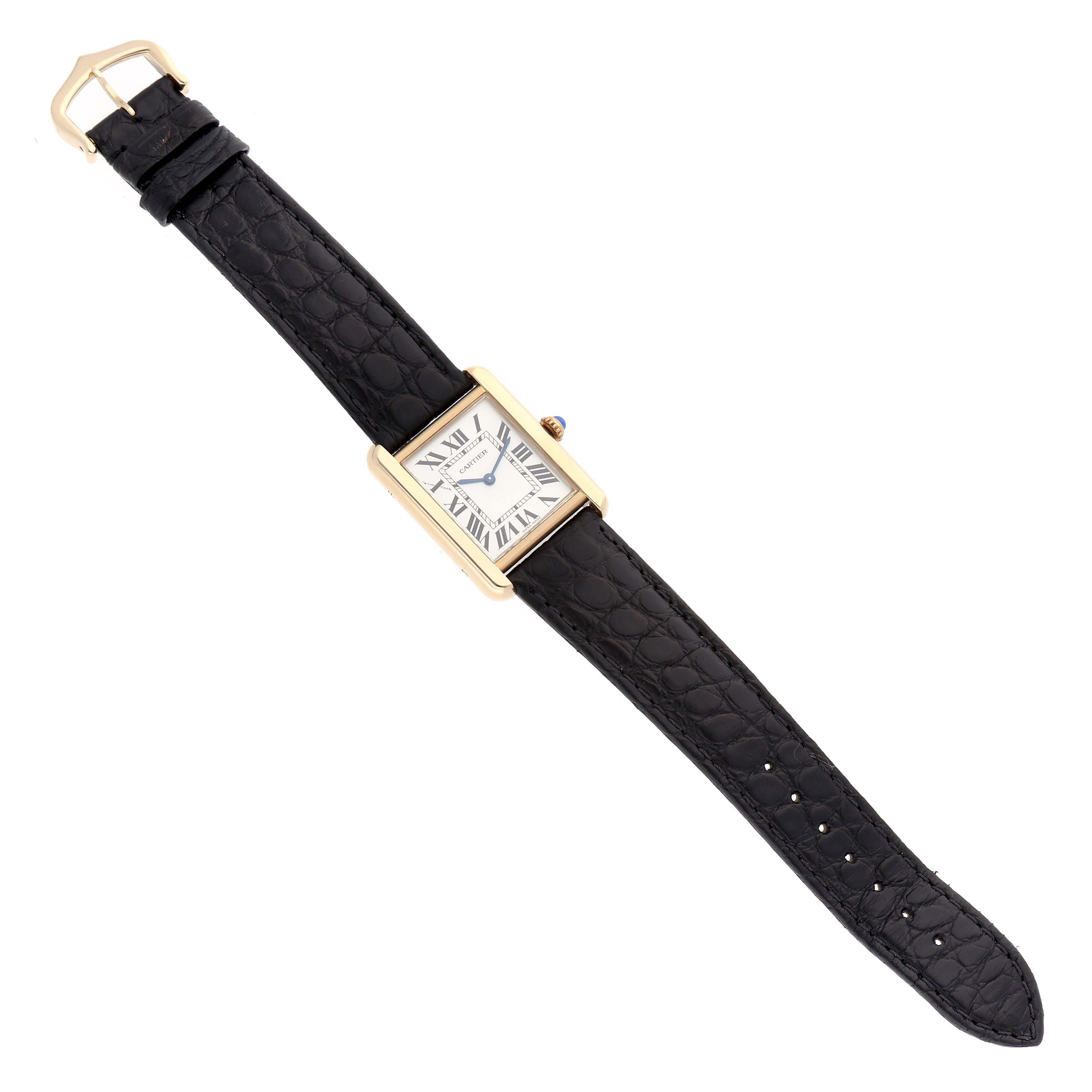 The Cartier Tank Solo W1018755 Women
s Yellow Gold Silver Dial watch is shown from a top view, highlighting the gold case, black leather strap, and clasp.