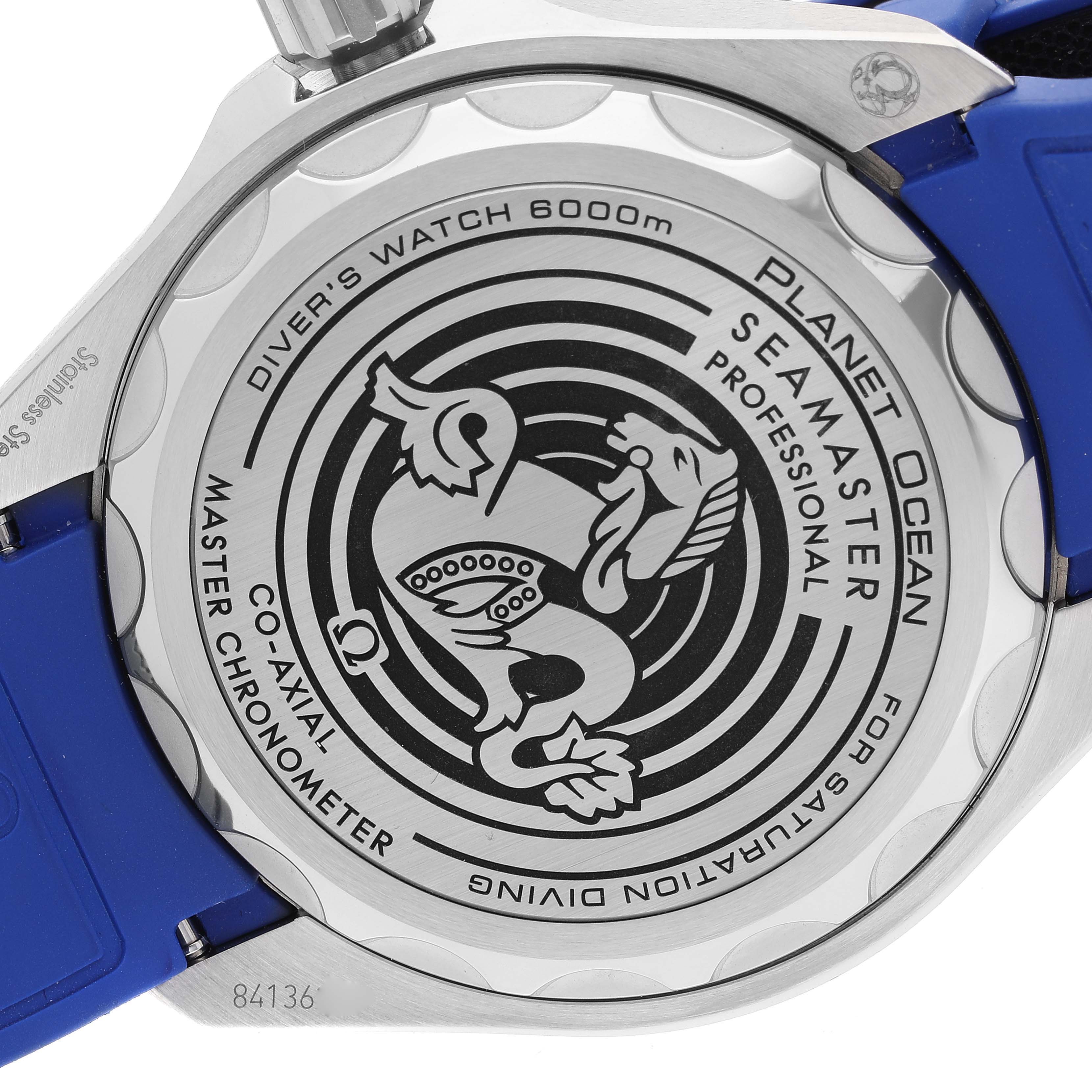 The image shows the back of an Omega Planet Ocean 215.32.46.21.04.001 Men's Stainless Steel White Dial 215.32.46.21.04.001 Men's Stainless Steel White Dial Seamaster watch, highlighting its engraved details and blue strap.