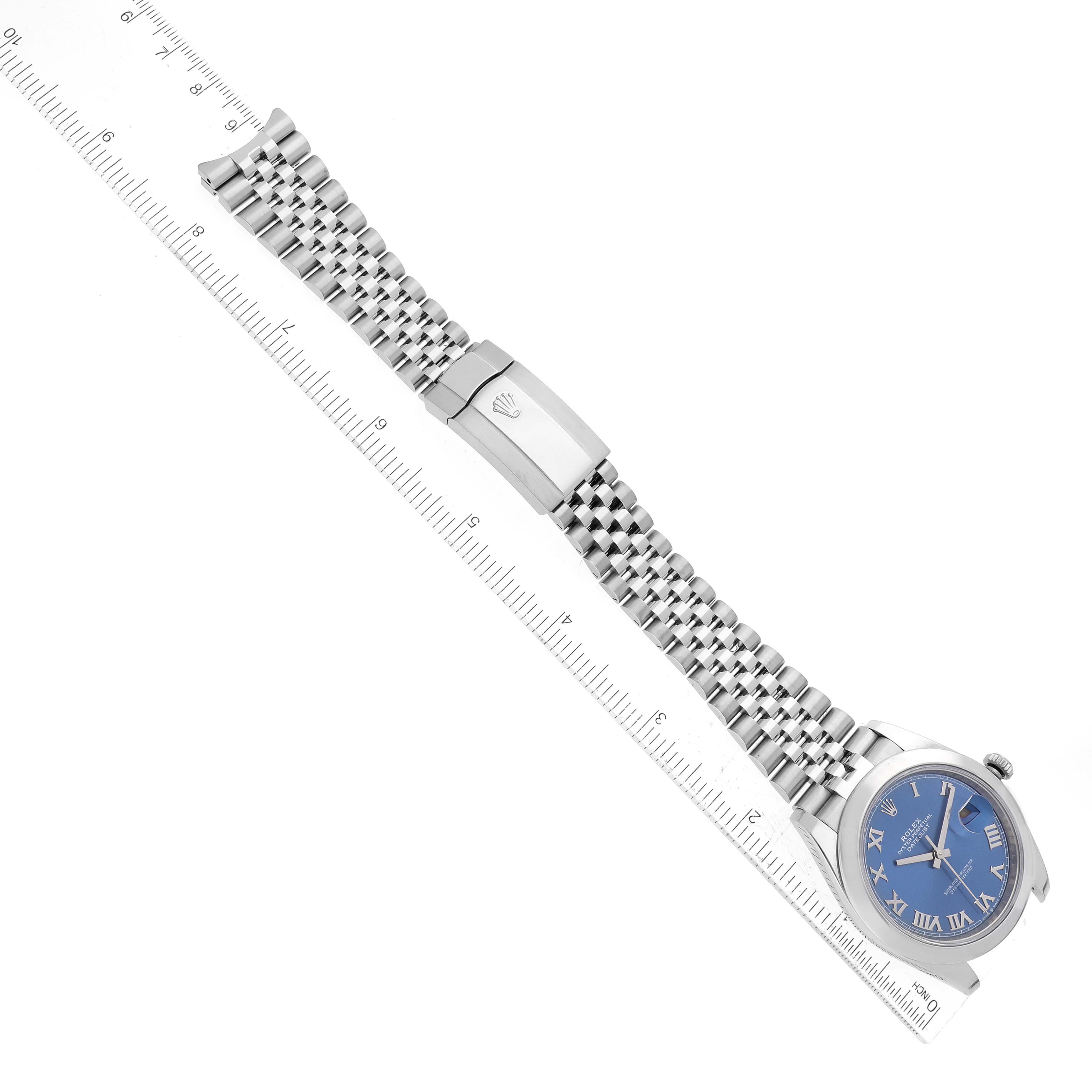 The Rolex Datejust 41 126300 Men's Stainless Steel Blue Dial 126300 Men's Stainless Steel Blue Dial watch is shown in a flat lay angle, displaying its silver bracelet and blue dial against a measuring ruler.