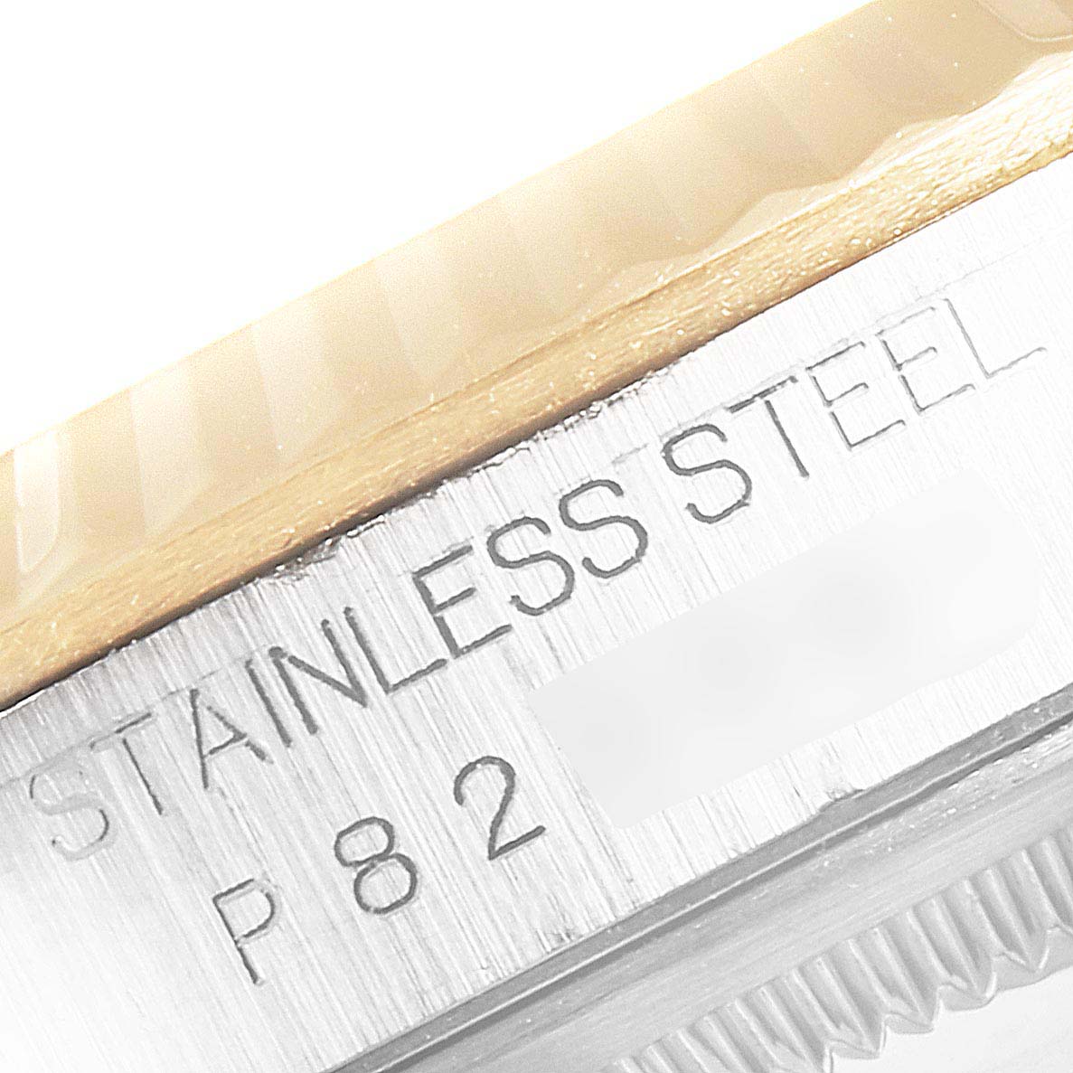 This image shows an angled close-up of the engraved "Stainless Steel" text and part of the fluted bezel on a Rolex Datejust 16233 Men
s Steel and Gold (two tone) Champagne Dial 16233 Men
s Steel and Gold (two tone) Champagne Dial.