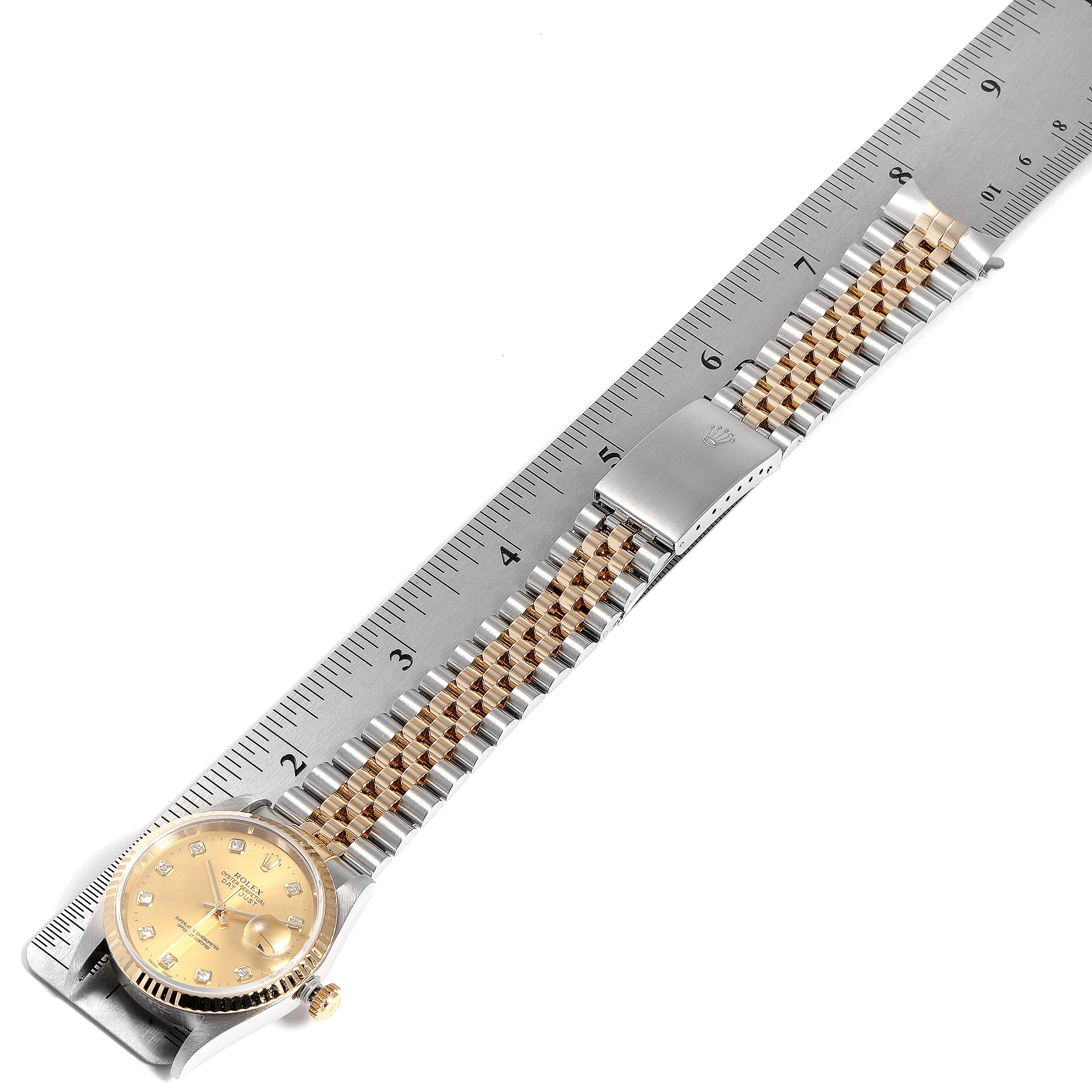 This image shows a Rolex Datejust 16233 Men
s Steel and Gold (two tone) Champagne Dial 16233 Men
s Steel and Gold (two tone) Champagne Dial watch featuring its bracelet and clasp at an overhead angle next to a ruler.