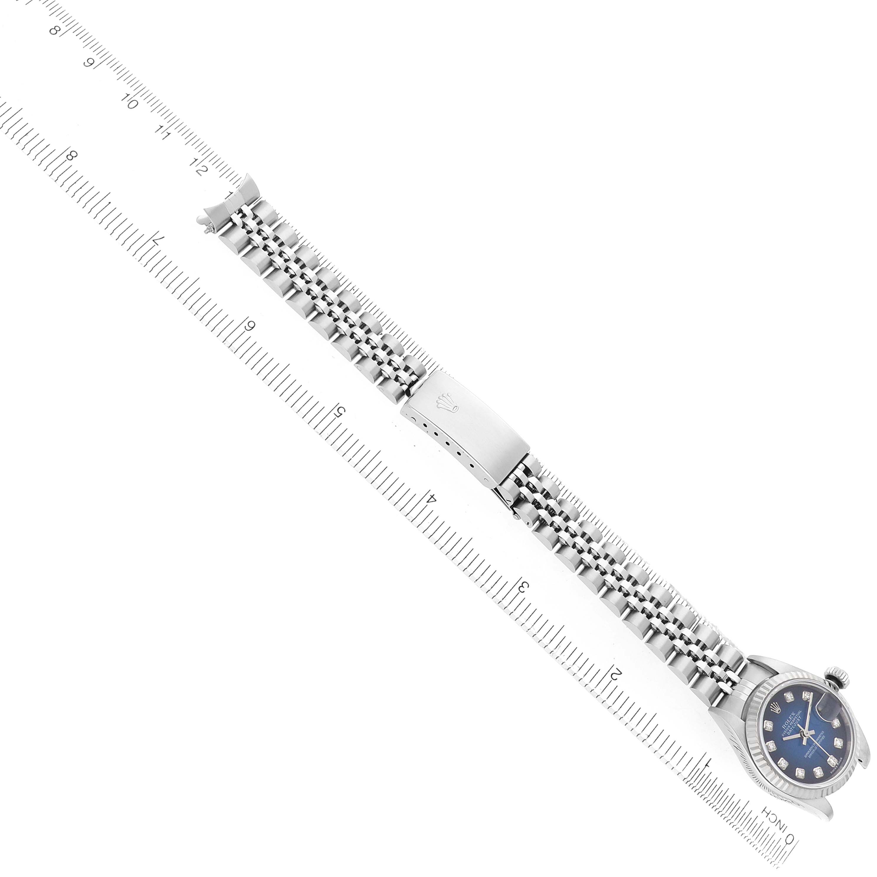 The Rolex Datejust 79174 Women's Stainless Steel Blue Dial watch is shown from a top-down angle, highlighting the bracelet, clasp, and face, alongside a measurement ruler.