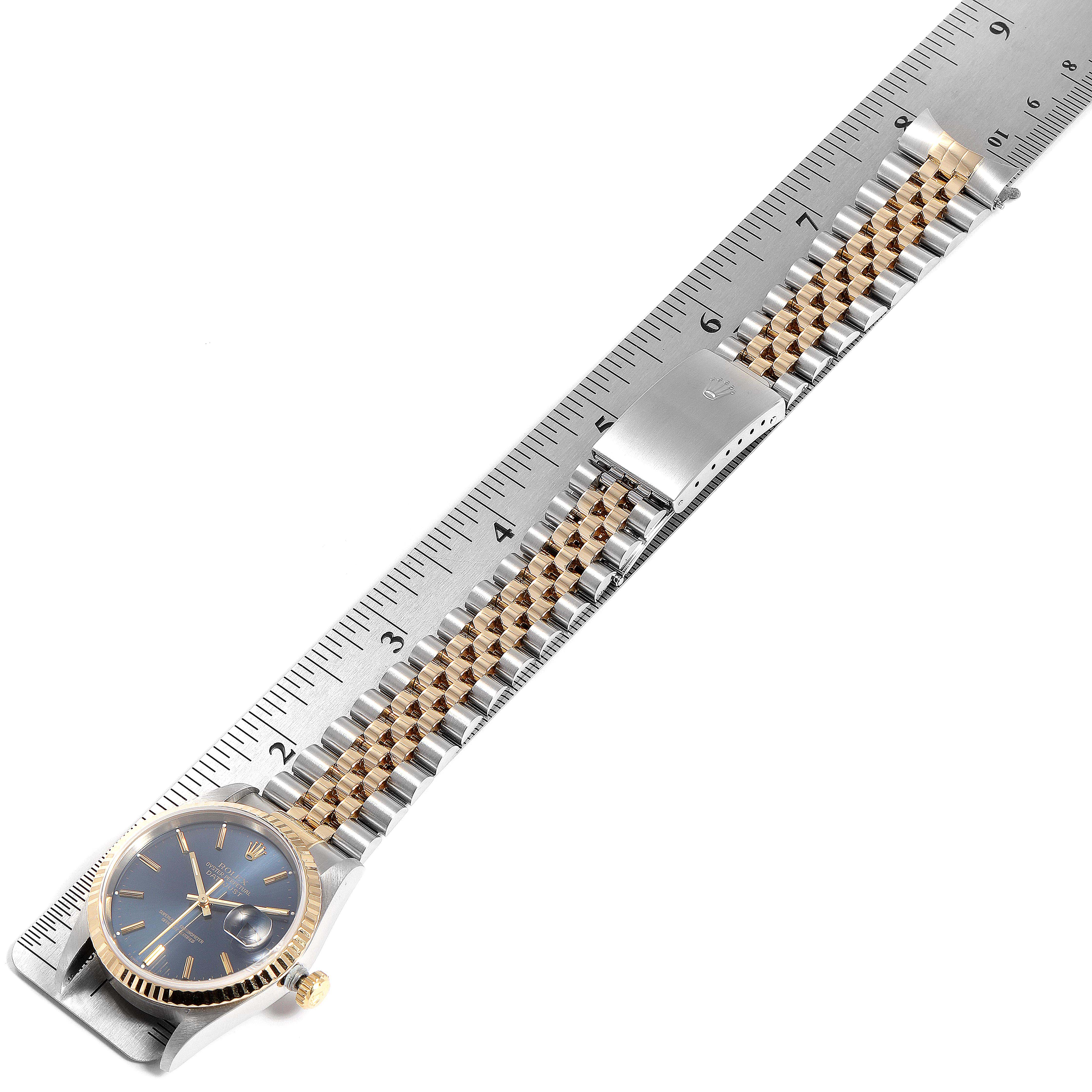 The image shows a Rolex Datejust 16233 Men's Steel and Gold (two tone) Blue Dial 16233 Men's Steel and Gold (two tone) Blue Dial watch laid flat with its bracelet extended next to a ruler for measurement.