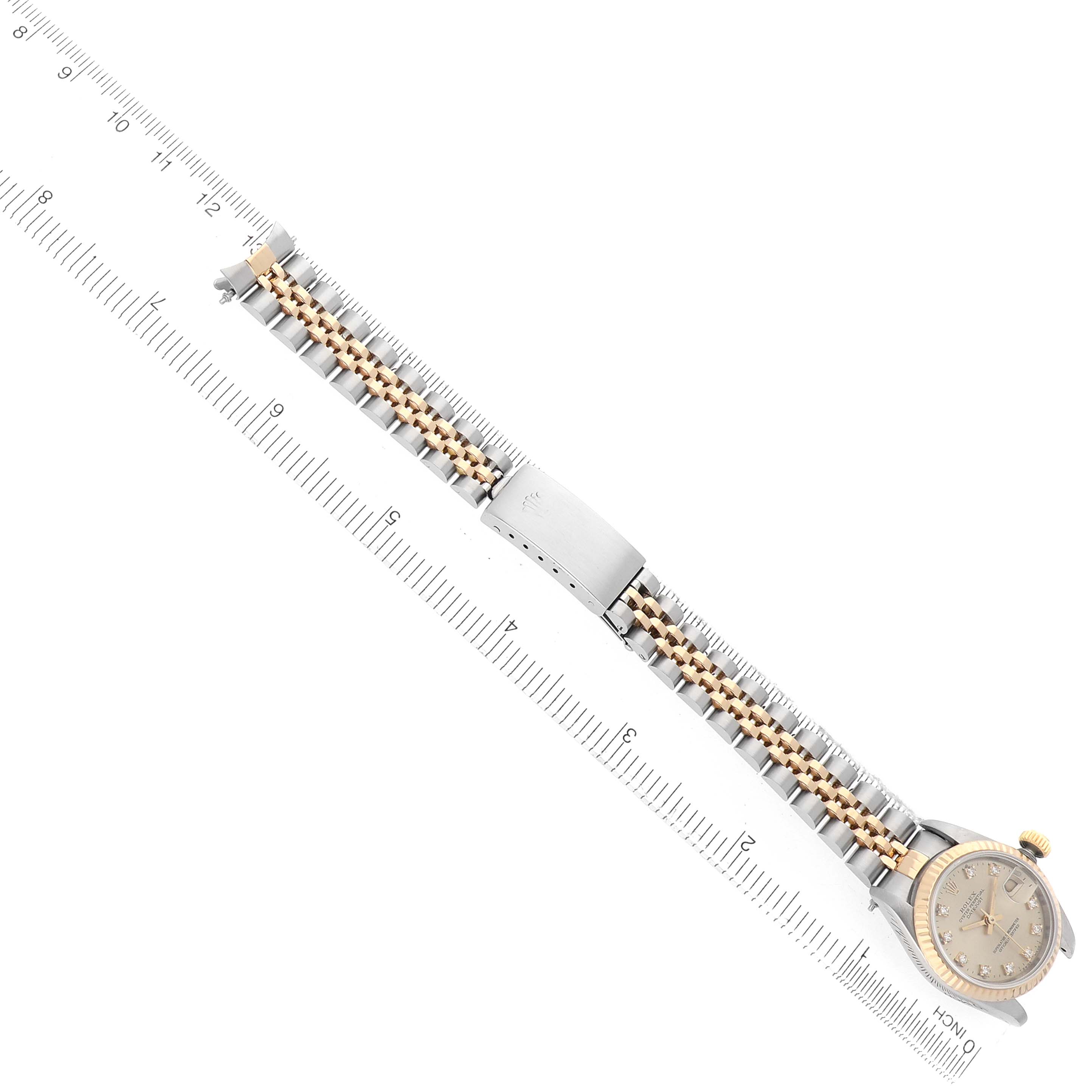 The Rolex Datejust 69173 Women's Steel and Gold (two tone) Champagne Dial watch is shown from a top-down angle with the entire bracelet and case visible, alongside a ruler for scale.
