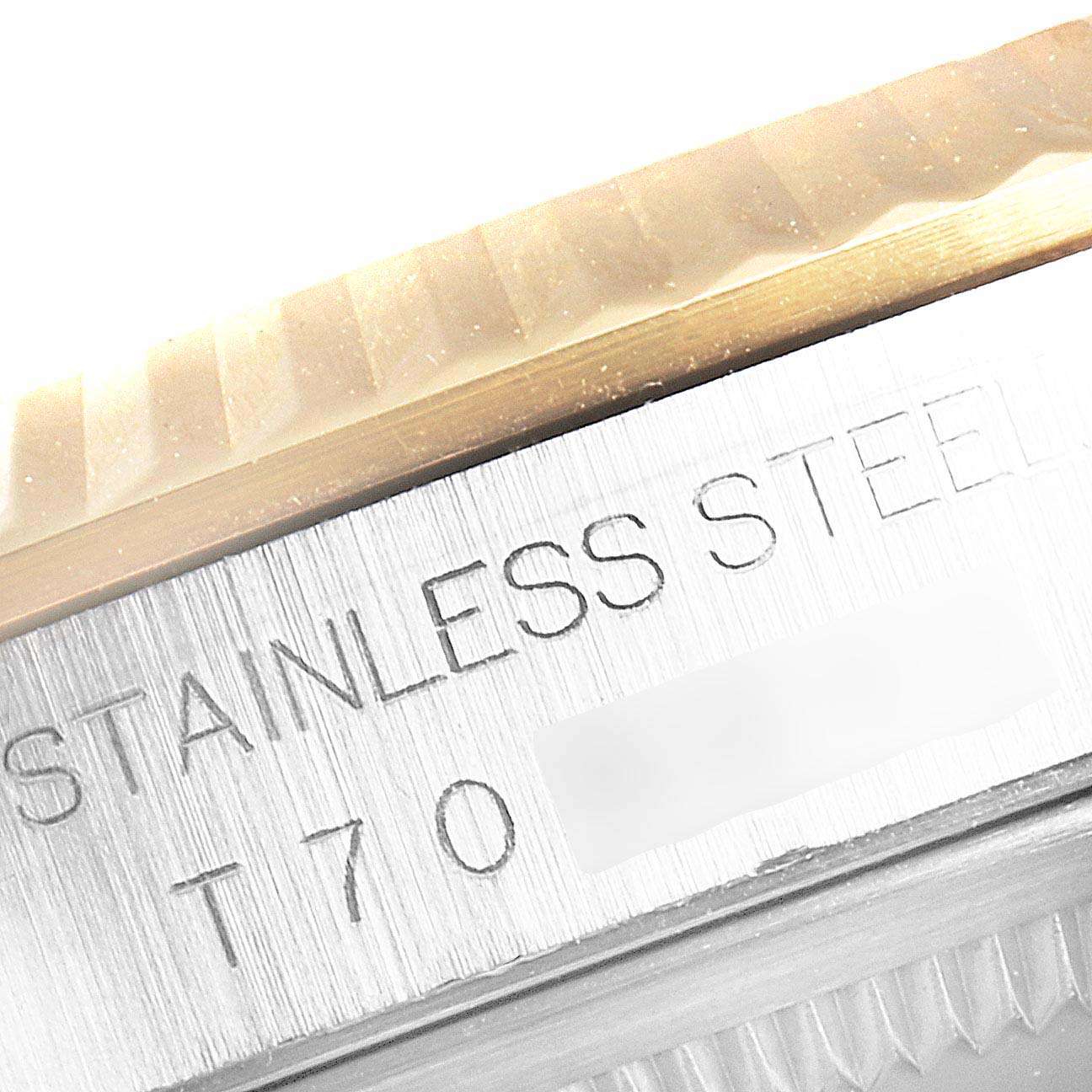 This close-up image of a Rolex Datejust 16233 Men
s Steel and Gold (two tone) White Dial 16233 Men
s Steel and Gold (two tone) White Dial watch shows a portion of the bezel and the engraved text on the stainless steel back.