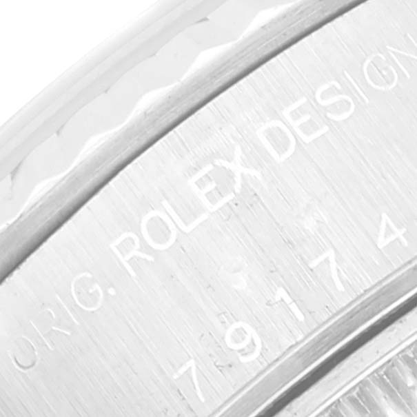 The image shows a close-up of the casing of a Rolex Datejust 79174 Women's Stainless Steel White Dial 79174 Women's Stainless Steel White Dial watch with engraved text and part of the fluted bezel.