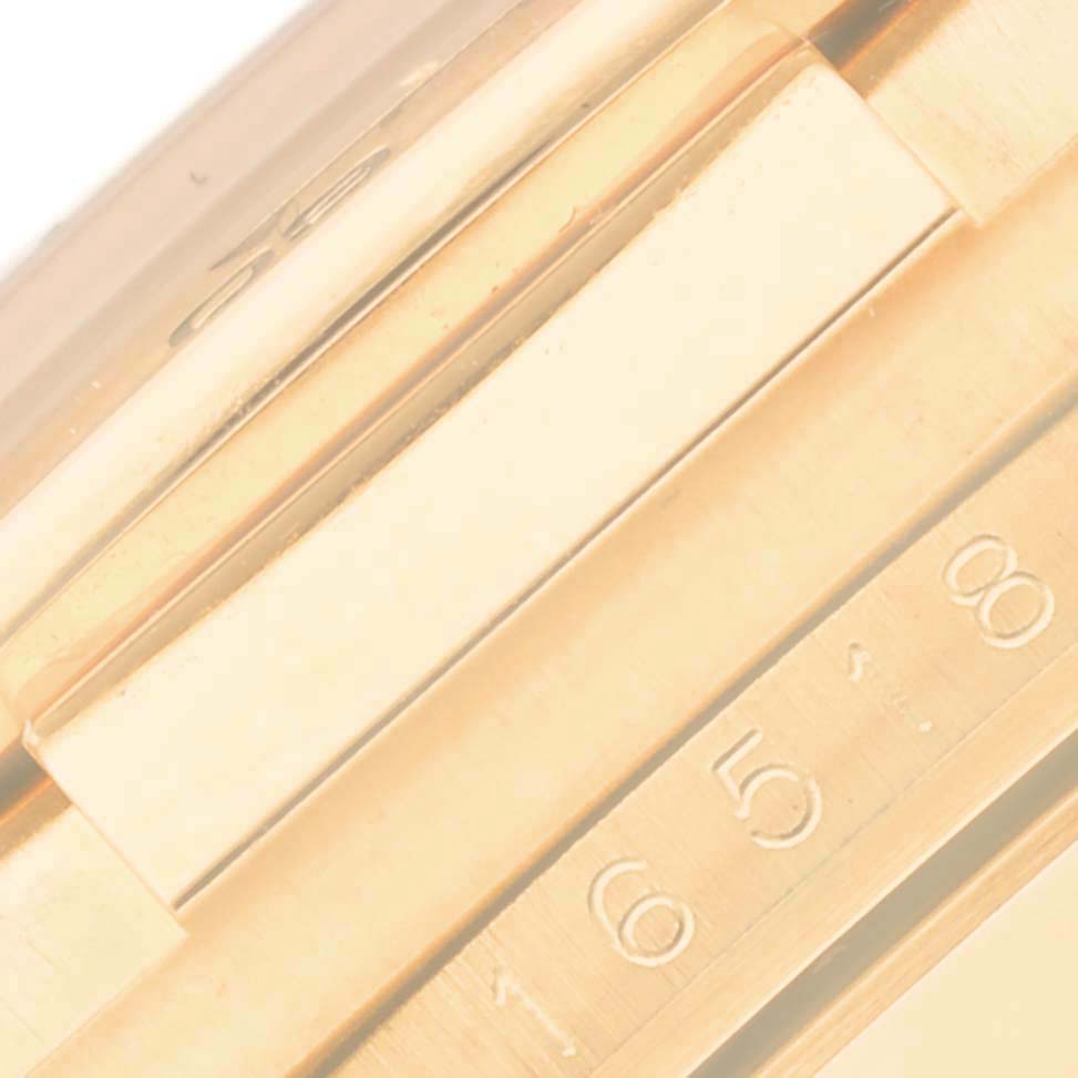 The image shows a close-up of the gold bezel and part of the strap of a Rolex Daytona 16518 Men's Yellow Gold Black Dial 16518 Men's Yellow Gold Black Dial watch.