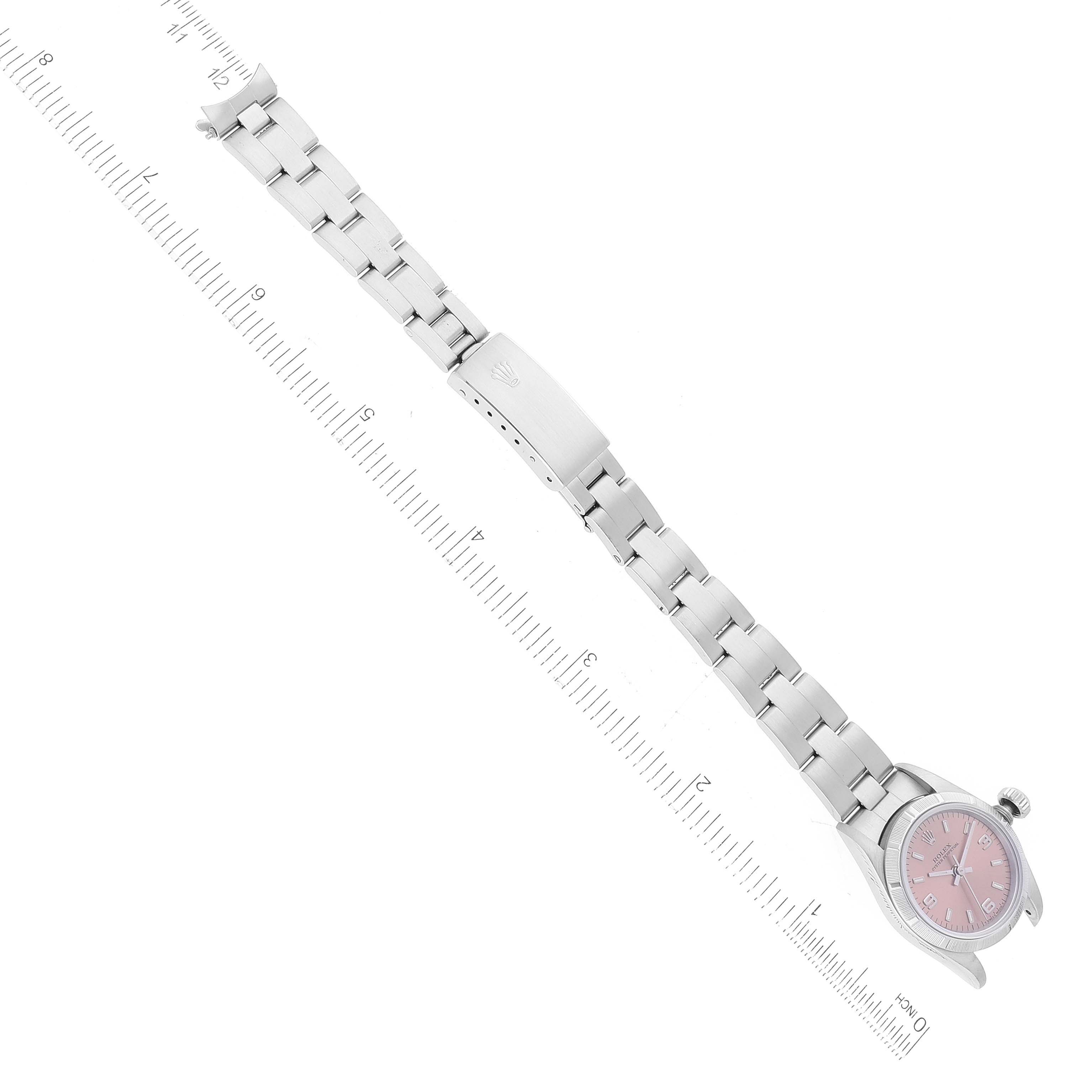 The image shows a top-down view of a Rolex Oyster Perpetual 67230 Women's Stainless Steel Pink Dial 67230 Women's Stainless Steel Pink Dial watch, highlighting its bracelet and pink dial.
