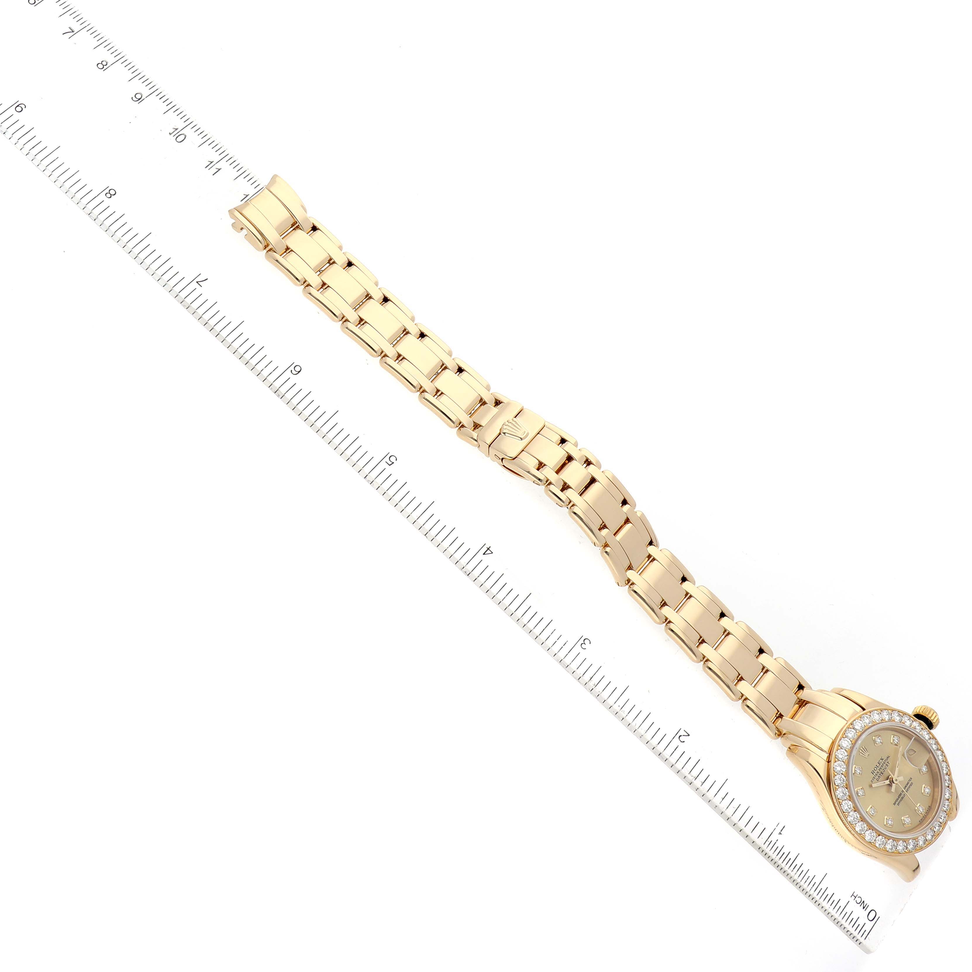 The image shows the full length of the Rolex Pearlmaster 69298 Women's Yellow Gold Champagne Dial 69298 Women's Yellow Gold Champagne Dial watch laid flat, next to a ruler for scale.