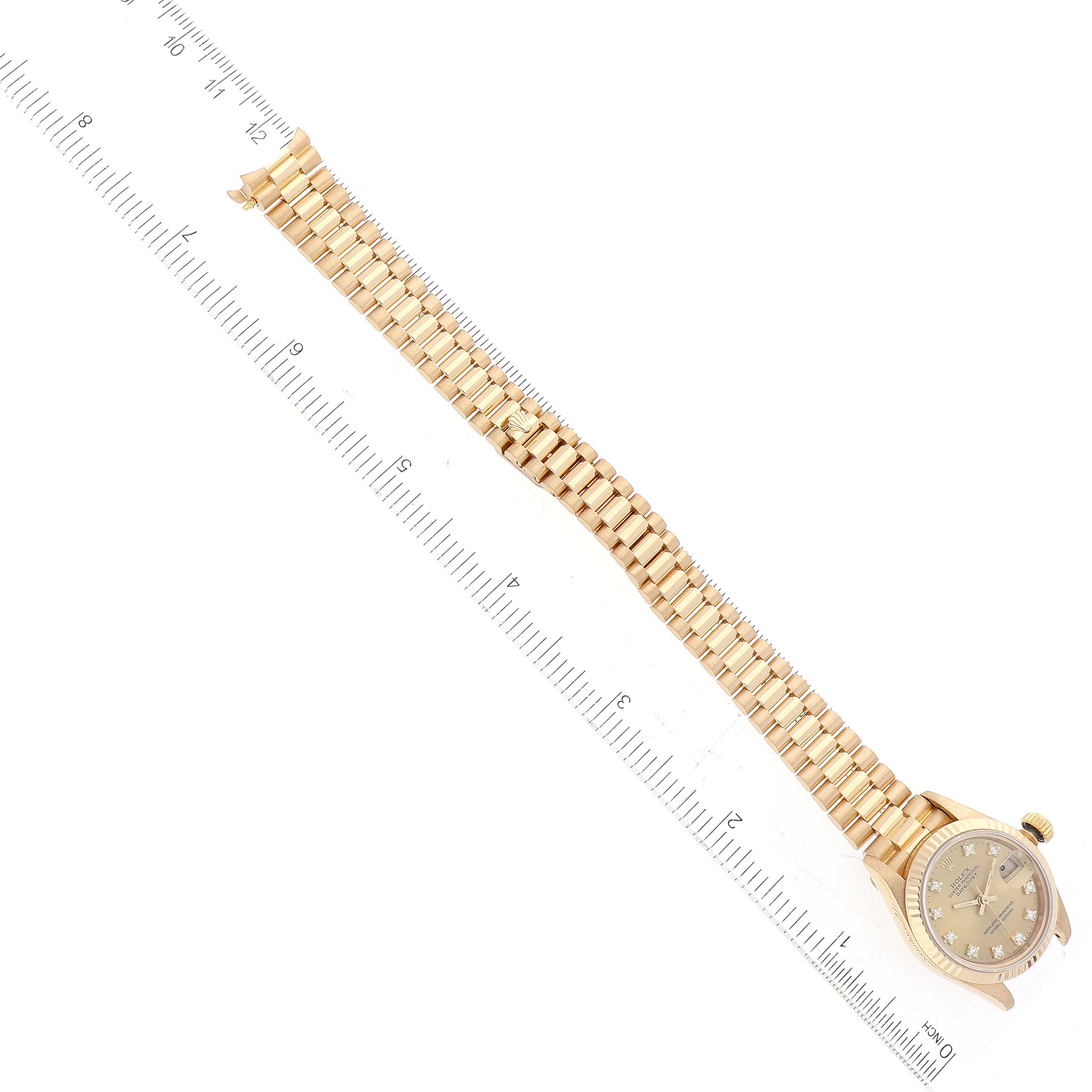 The image shows a Rolex President 69178 Women
s Yellow Gold Champagne Dial 69178 Women
s Yellow Gold Champagne Dial model watch laid flat with a ruler beside it for measurement.
