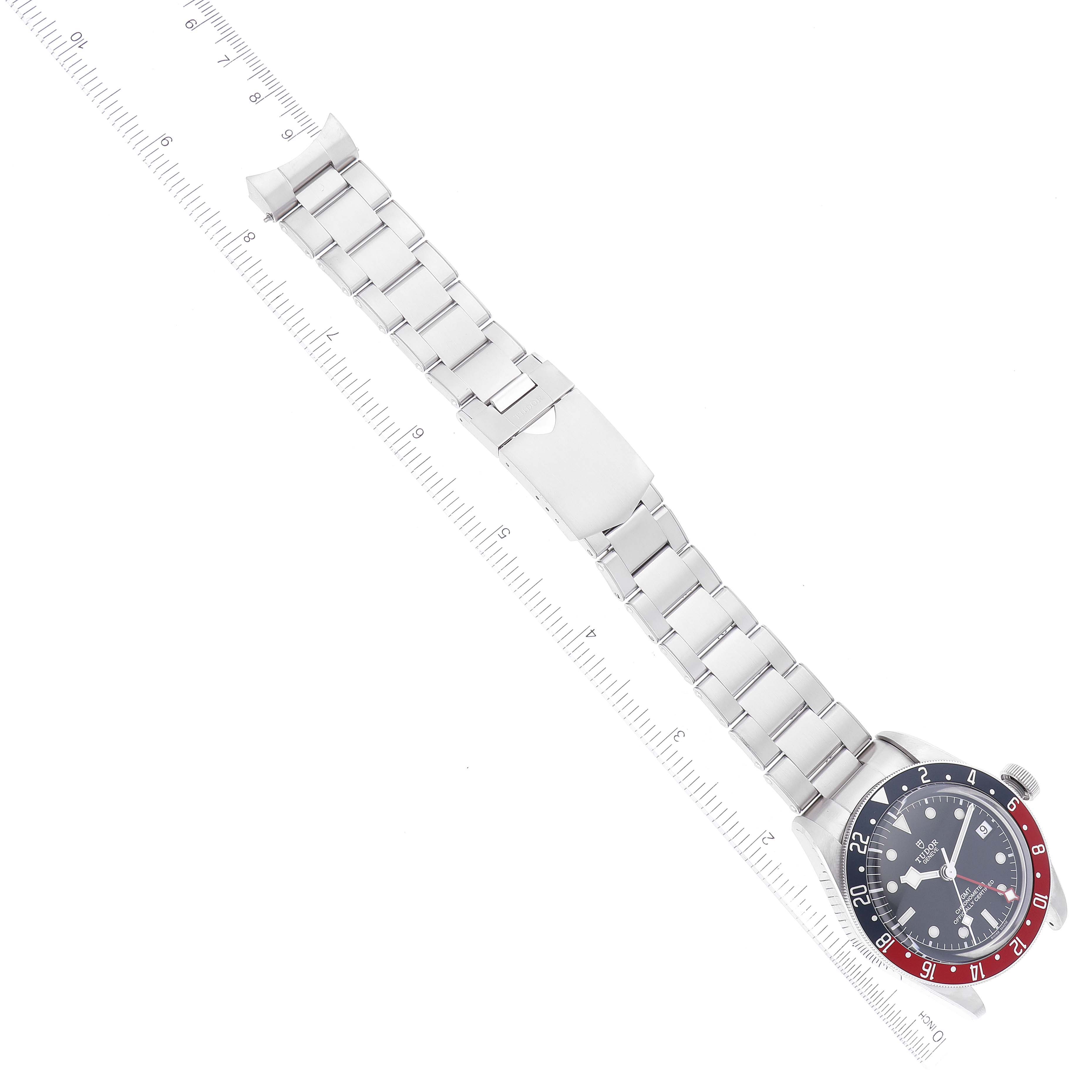 The image shows a Tudor Heritage Black Bay 79830RB Men
s Stainless Steel Black Dial 79830RB Men
s Stainless Steel Black Dial watch laid flat with a metal bracelet and a ruler for scale.