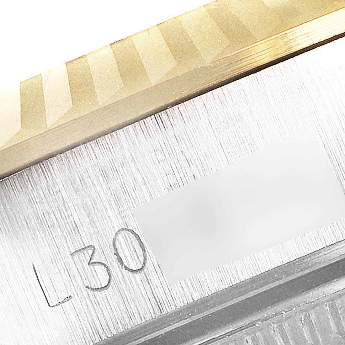 The image shows a close-up of the fluted bezel and part of the case with an engraving on a Rolex Datejust 67193 Women
s Steel and Gold (two tone) White Dial 67193 Women
s Steel and Gold (two tone) White Dial watch.