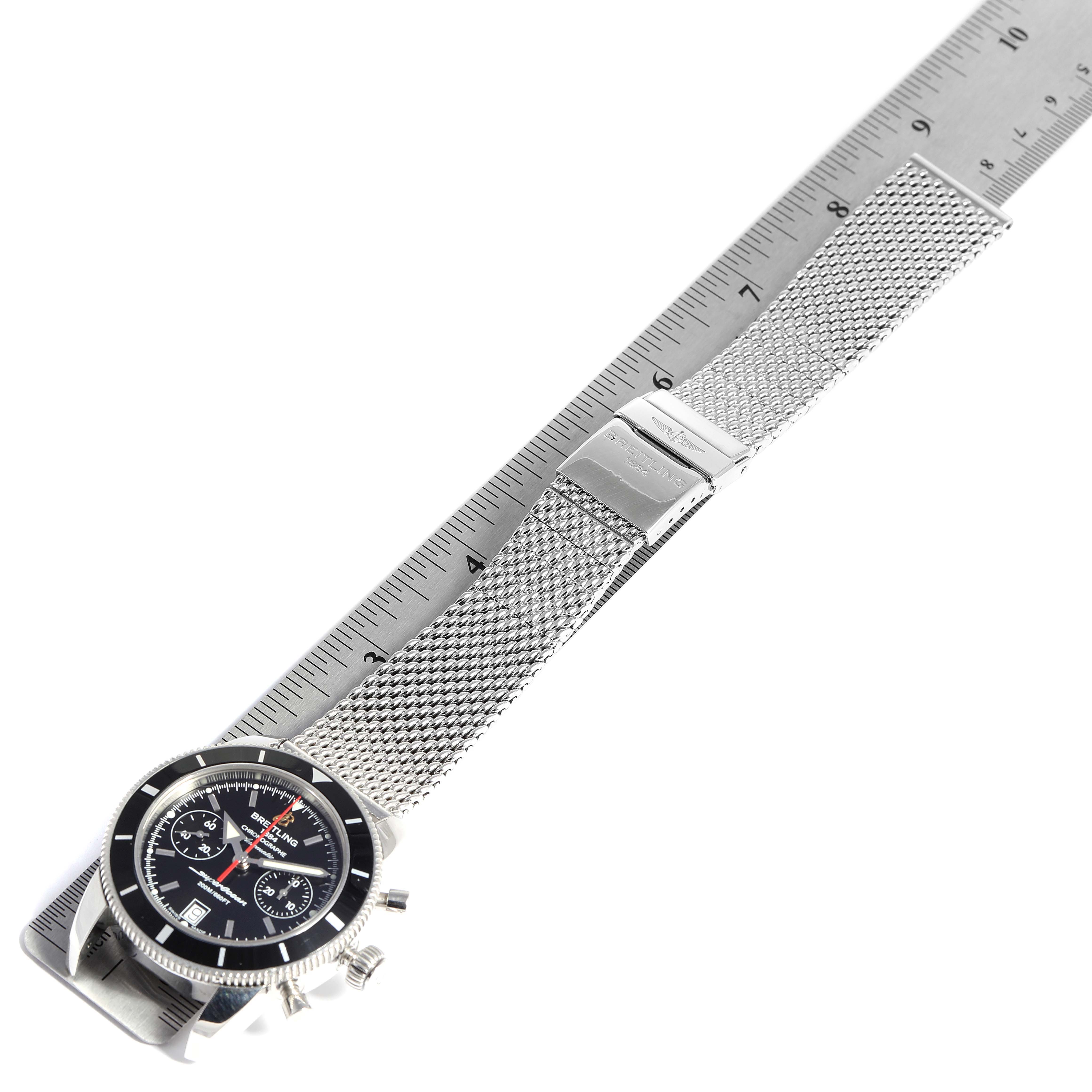 The Breitling Superocean A23370 Men's Stainless Steel Black Dial A23370 Men's Stainless Steel Black Dial watch is shown from an oblique angle, featuring its dial, mesh bracelet, and clasp laid beside a ruler.