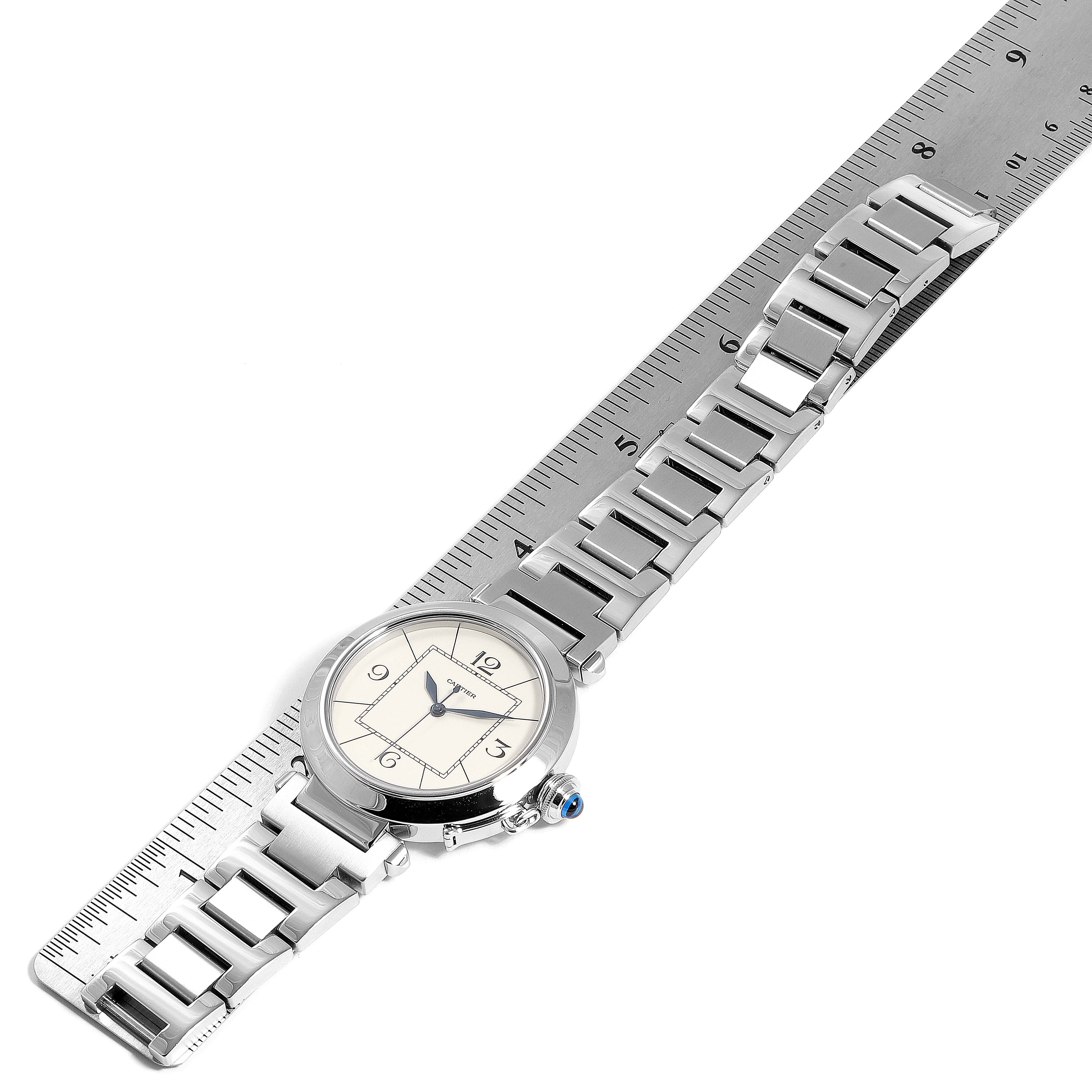 This image shows a Cartier Pasha W31072M7 Men's Stainless Steel Silver Dial W31072M7 Men's Stainless Steel Silver Dial watch laid flat next to a ruler, highlighting its face, band, and clasp.