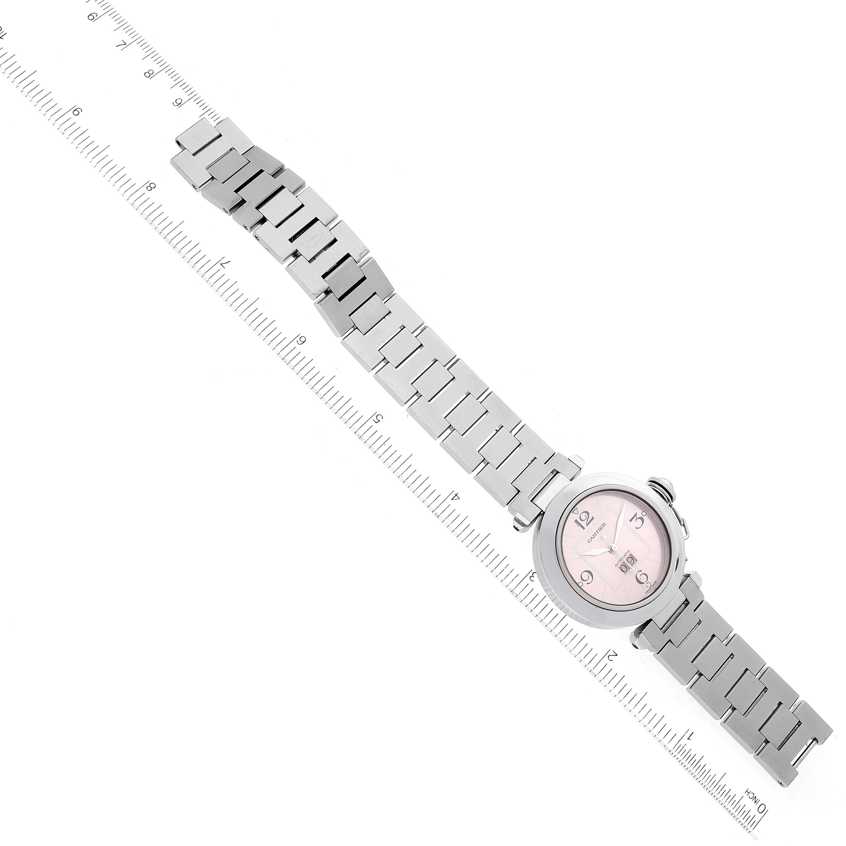 This image shows a full view from above of a Cartier Pasha W31058M7 Women's Stainless Steel Pink Dial W31058M7 Women's Stainless Steel Pink Dial watch with a pink face and metal bracelet next to a ruler.