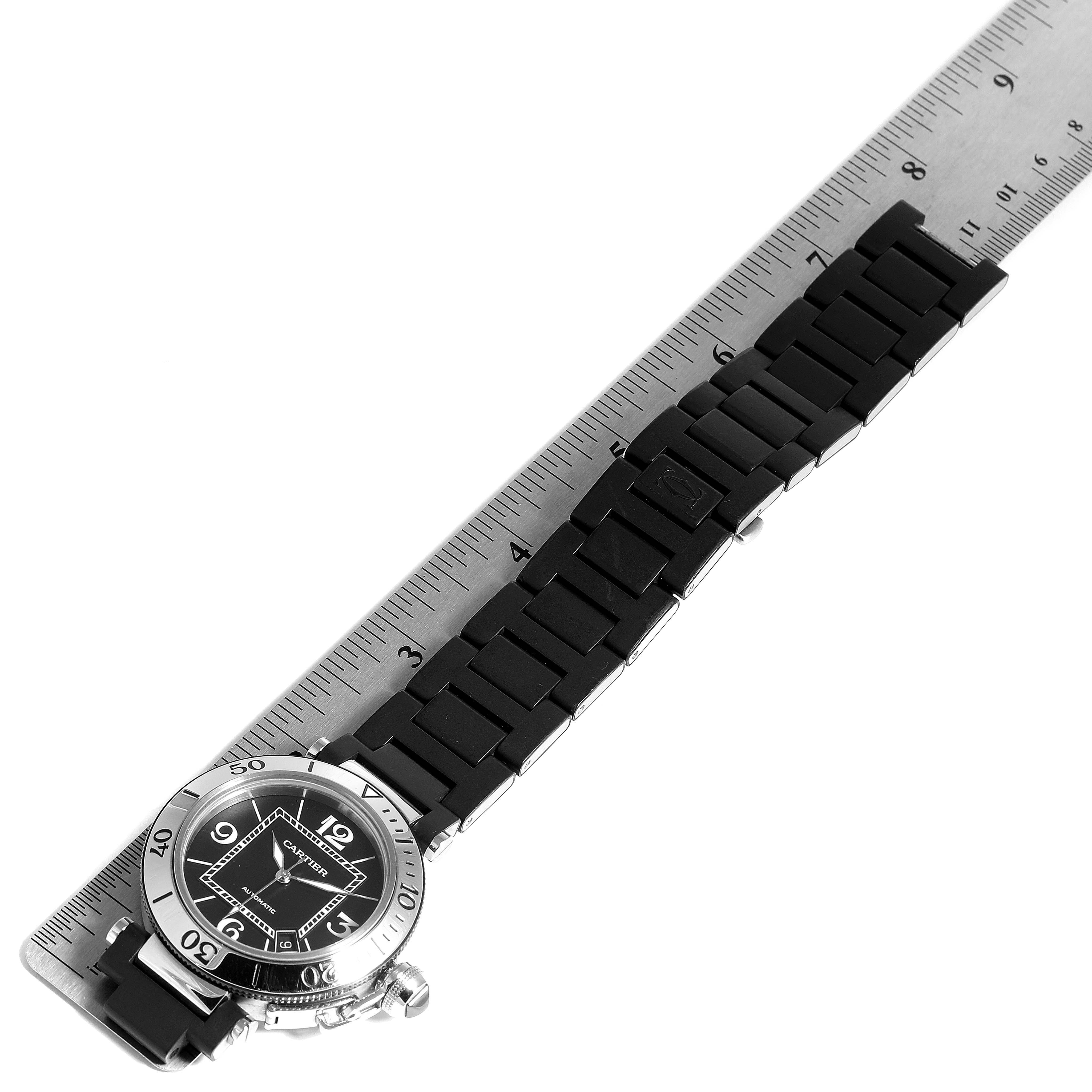 The image shows a Pasha model by Cartier laid flat with a ruler measuring its black strap and silver case.
