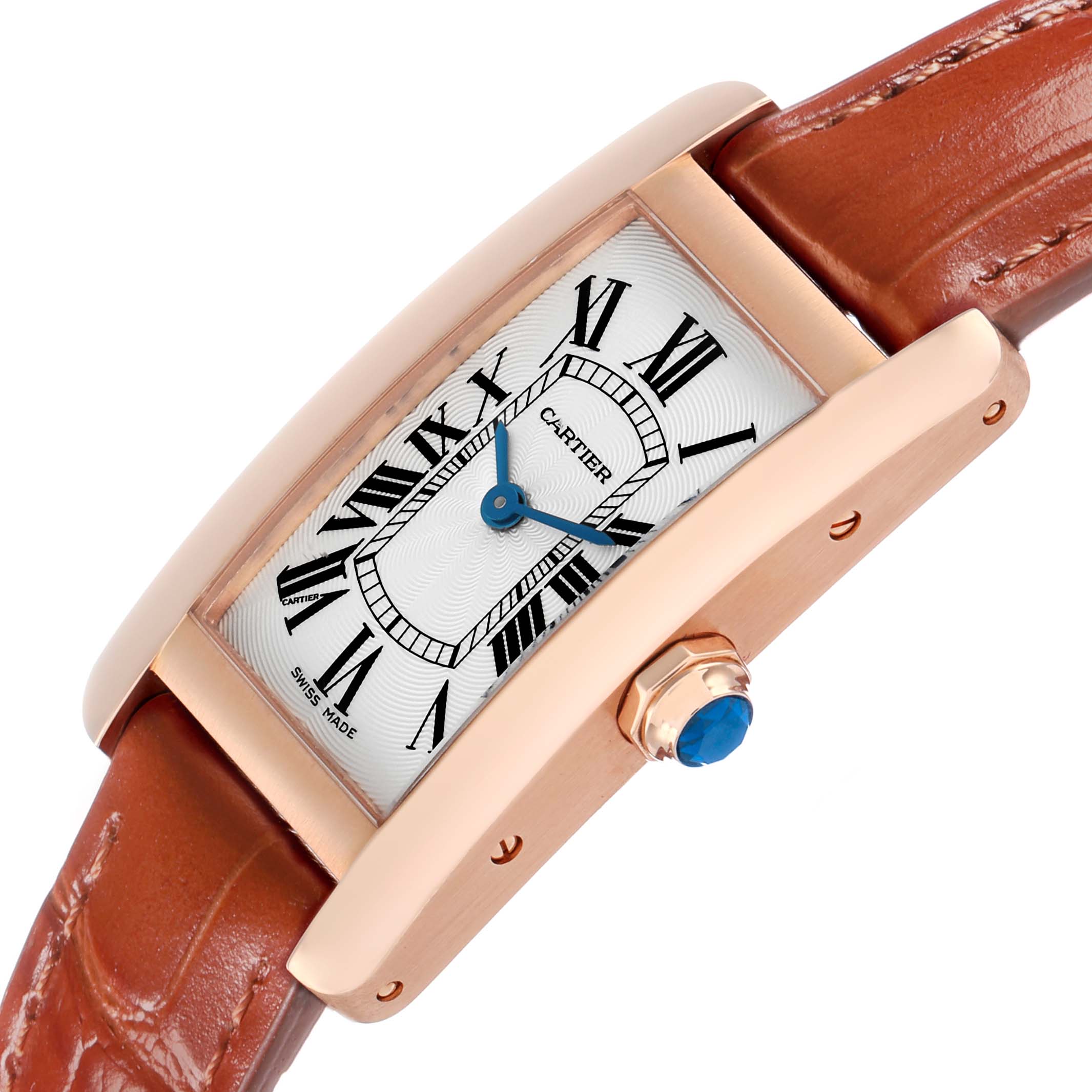 The Cartier Tank Americaine W2607456 Women's Rose Gold Silver Dial watch is shown at an angle highlighting the face, Roman numerals, blue hands, crown, and leather strap.