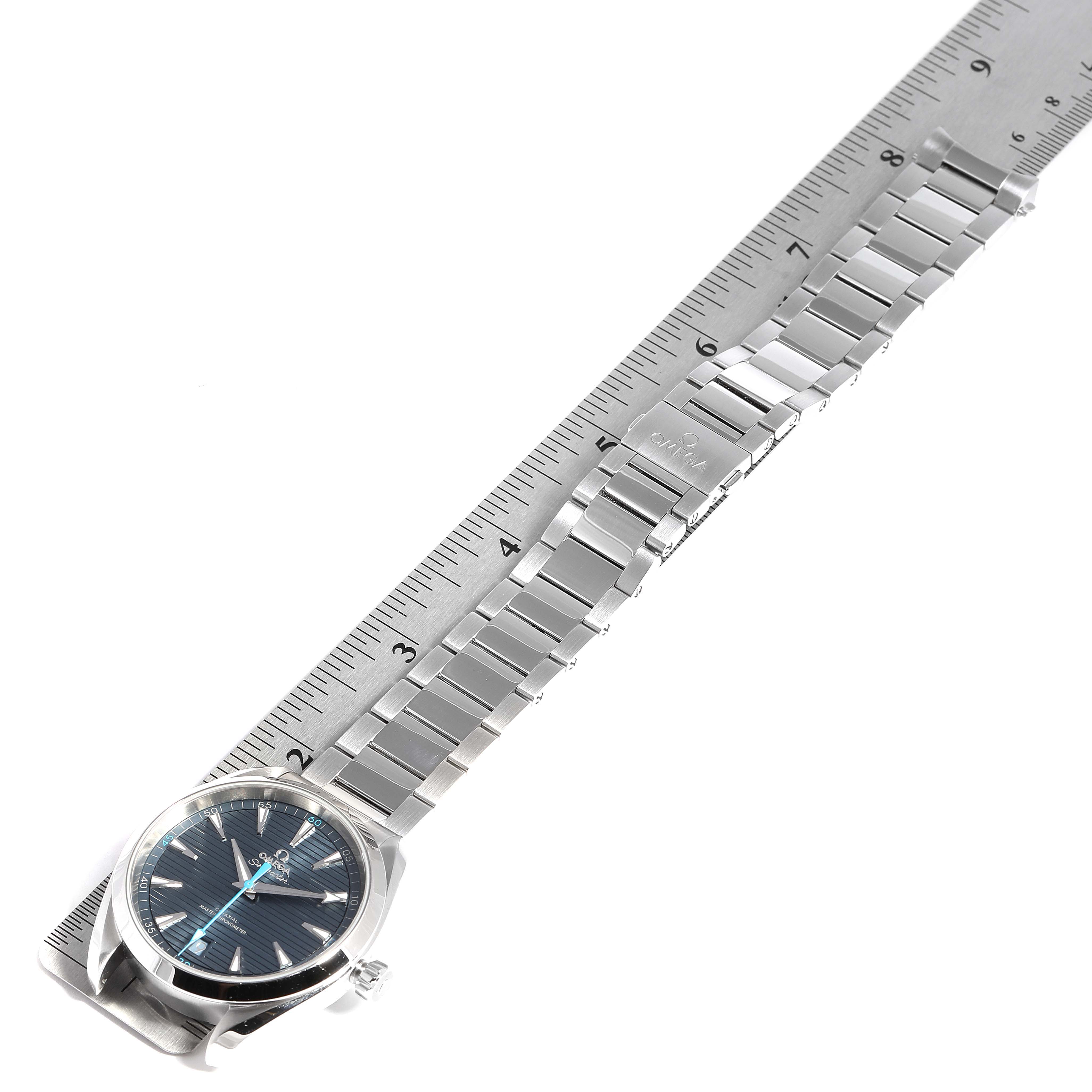This image shows an Omega Aqua Terra 220.10.41.21.03.002 Men's Stainless Steel Blue Dial 220.10.41.21.03.002 Men's Stainless Steel Blue Dial watch with its full metal bracelet laid alongside a ruler.