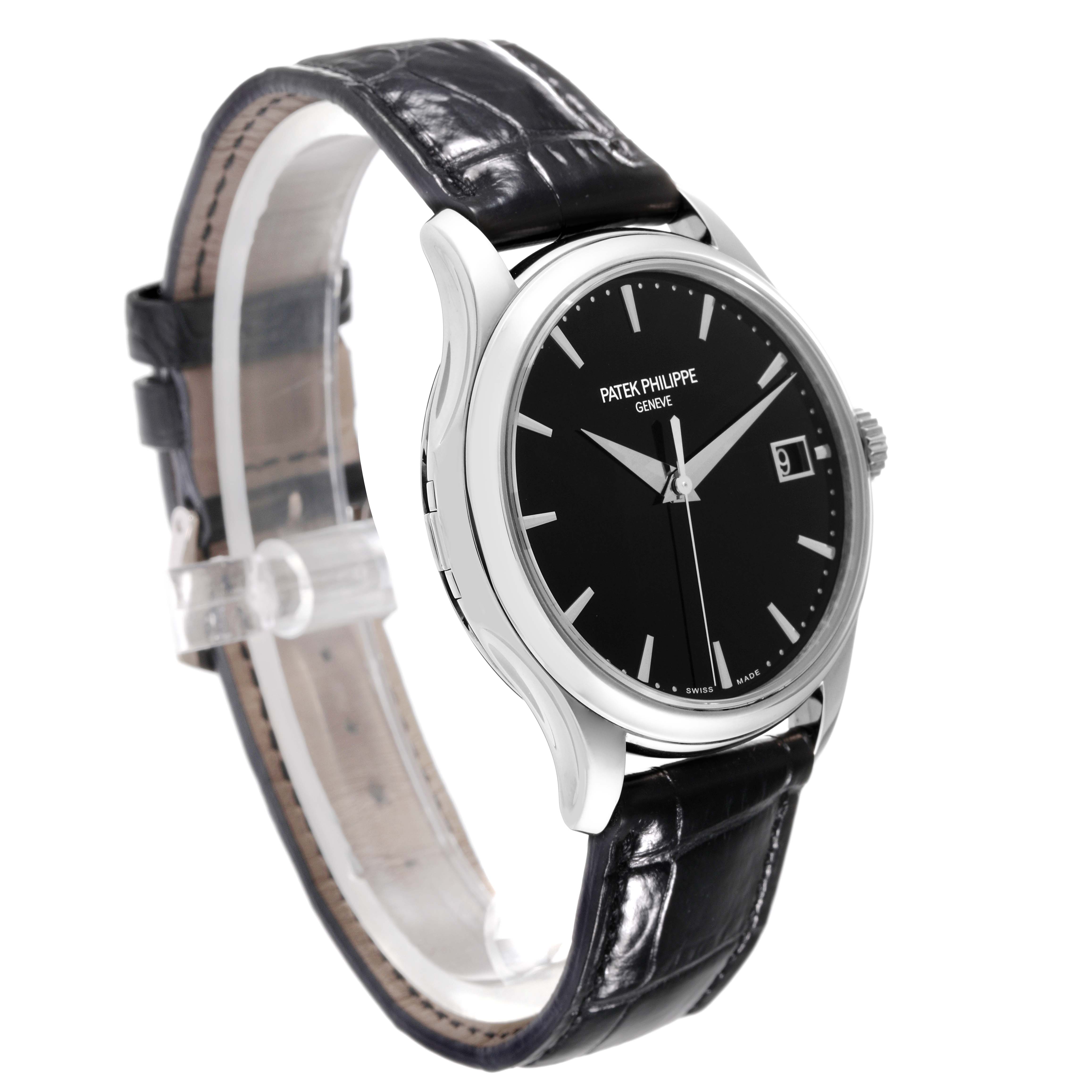 This image shows a Patek Philippe Calatrava 5227G-010 Men's White Gold Black Dial 5227G-010 Men's White Gold Black Dial watch at a three-quarter angle, highlighting its black dial, date window, and leather strap.