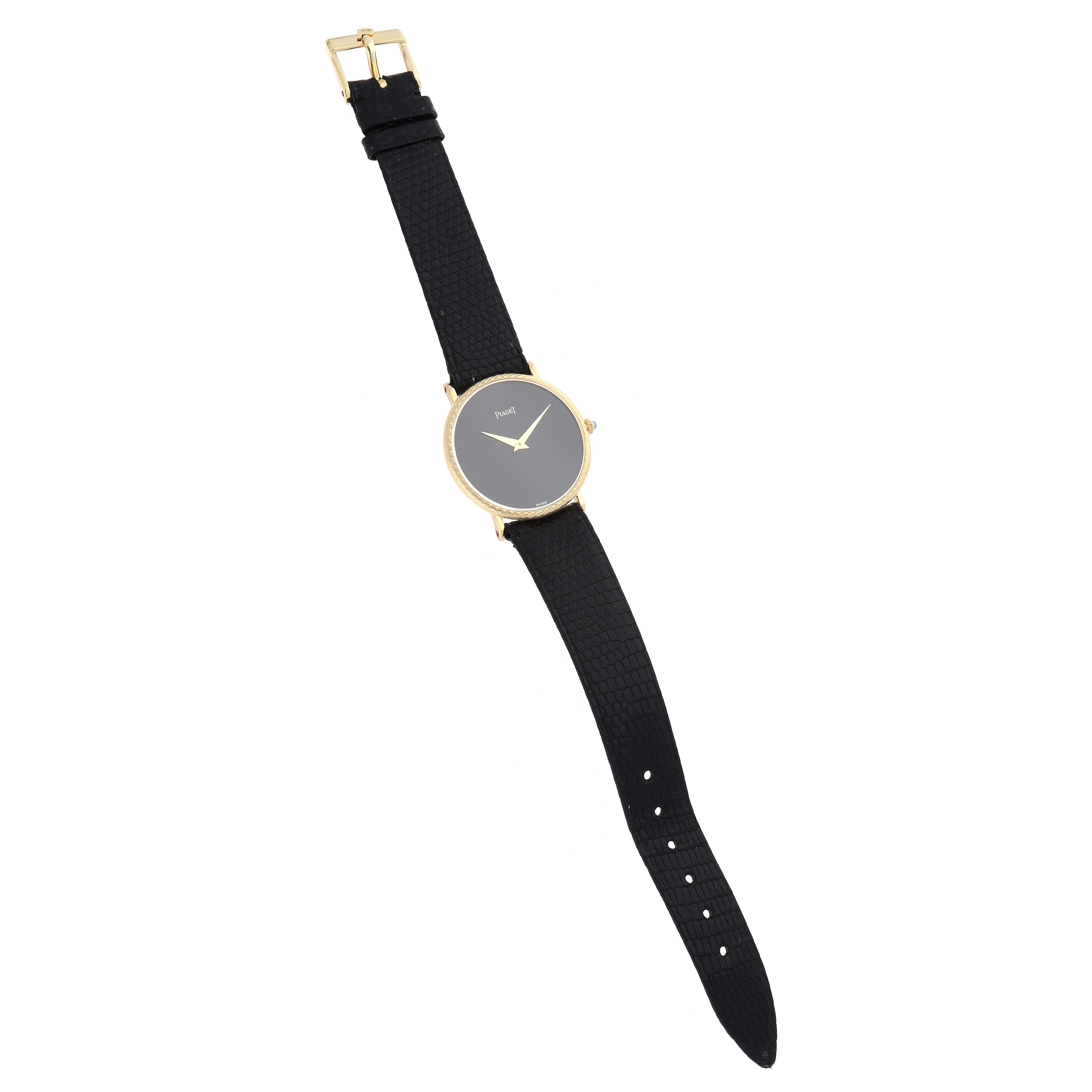 The Piaget 9026 Women's Yellow Gold Black Dial Dancer Vintage 9026 watch is shown from a top-down angle, displaying its black dial, yellow gold case, and black strap.
