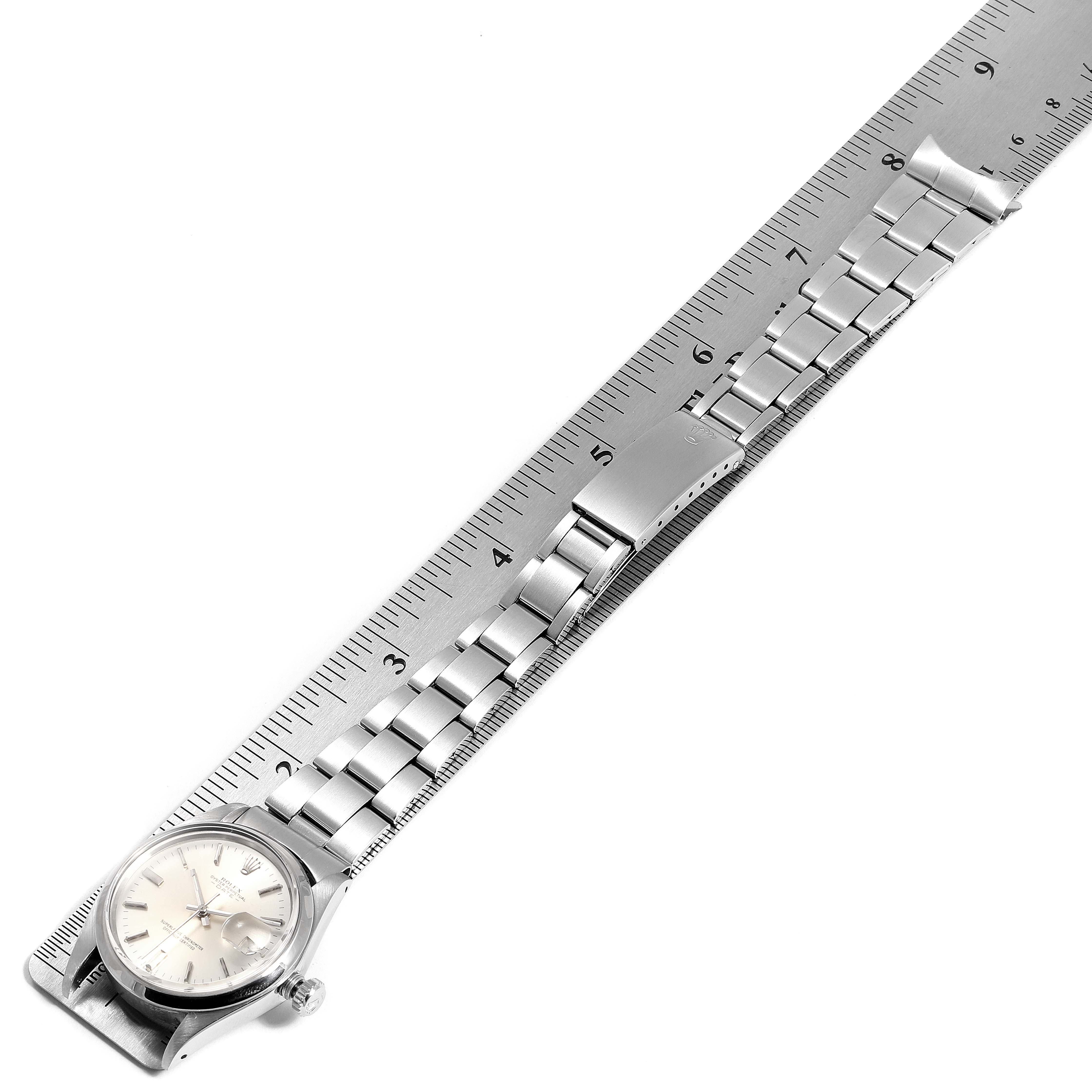 The Vintage Collection Rolex watch is shown from a top-down angle alongside a ruler, displaying its face and metal strap.