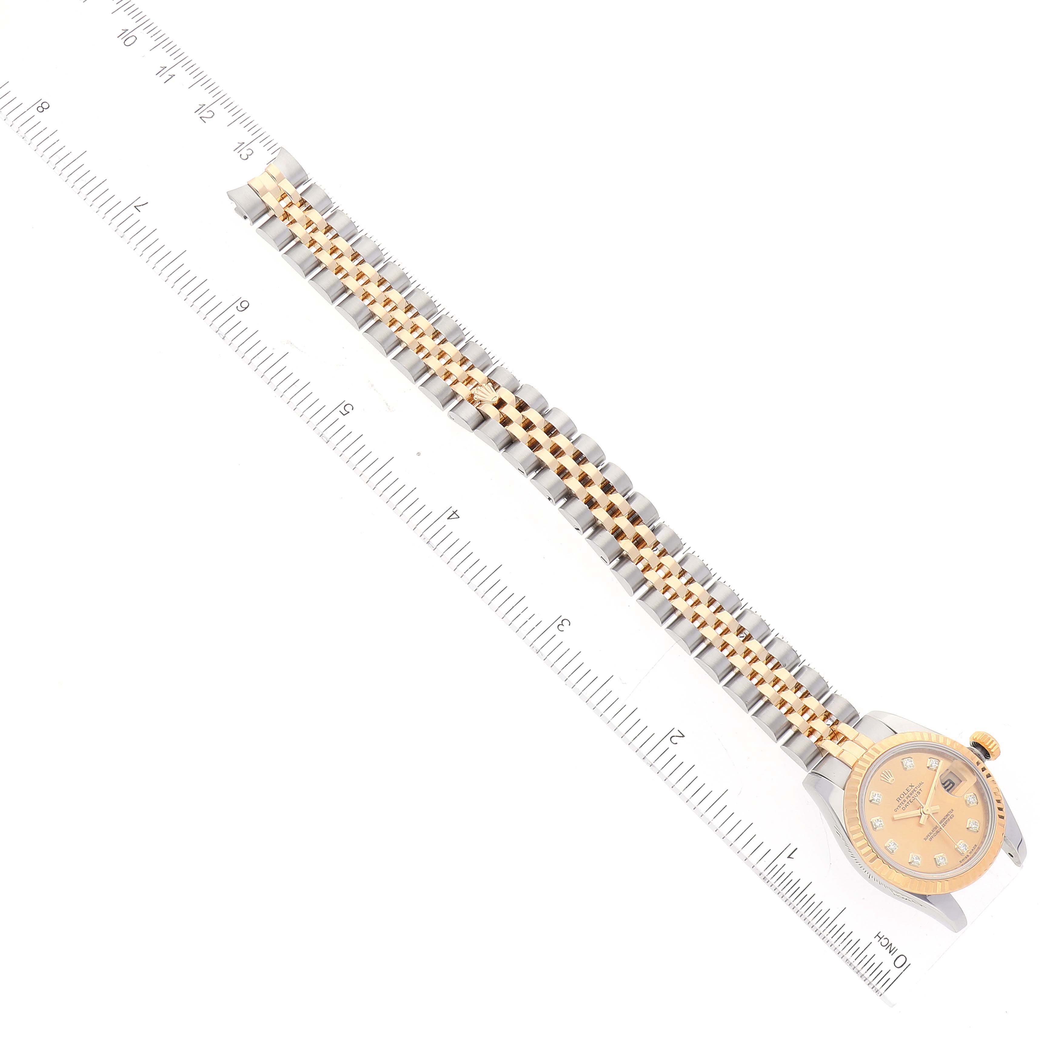 The image shows a Rolex Datejust 179173 Women's Steel and Gold (two tone) Champagne Dial 179173 Women's Steel and Gold (two tone) Champagne Dial watch laid flat, displaying the face and entire bracelet alongside a ruler for size reference.