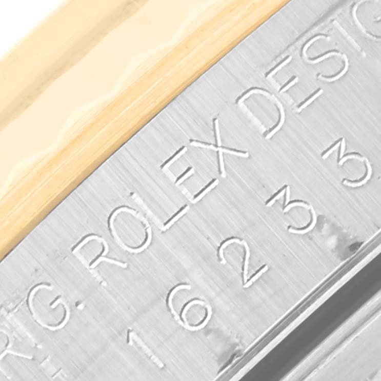 The image shows a close-up of a Rolex Datejust 16233 Men's Steel and Gold (two tone) Blue Dial 16233 Men's Steel and Gold (two tone) Blue Dial watch with visible engravings and part of the bezel.