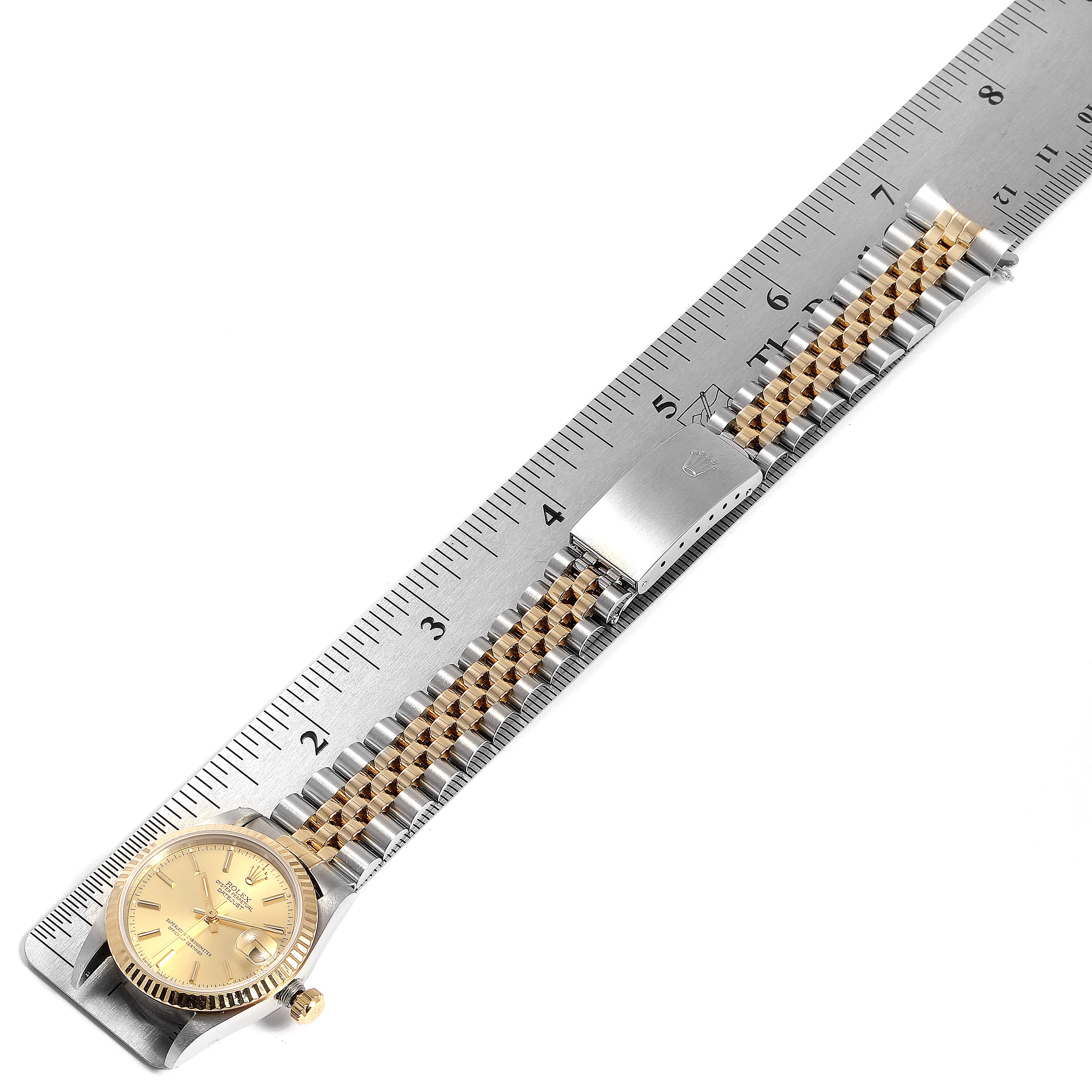 The image shows a Rolex Mid-Size 68273 Women
s Steel and Gold (two tone) Champagne Dial 68273 Women
s Steel and Gold (two tone) Champagne Dial watch laid flat next to a ruler, displaying its face and entire bracelet.