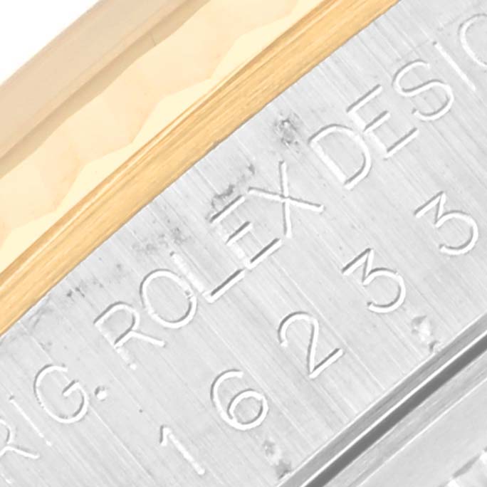 The image shows a close-up of the Rolex Datejust 16233 Men's Steel and Gold (two tone) Champagne Dial 16233 Men's Steel and Gold (two tone) Champagne Dial model's engraved bezel and part of the case.