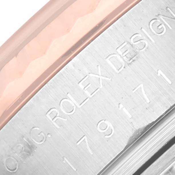 This image shows a close-up of the side engraving detailing "ORIG. ROLEX DESIGN" with a part of the bezel of a Rolex Datejust 179171 Women's Steel and Gold (two tone) Pink Dial 179171 Women's Steel and Gold (two tone) Pink Dial watch.
