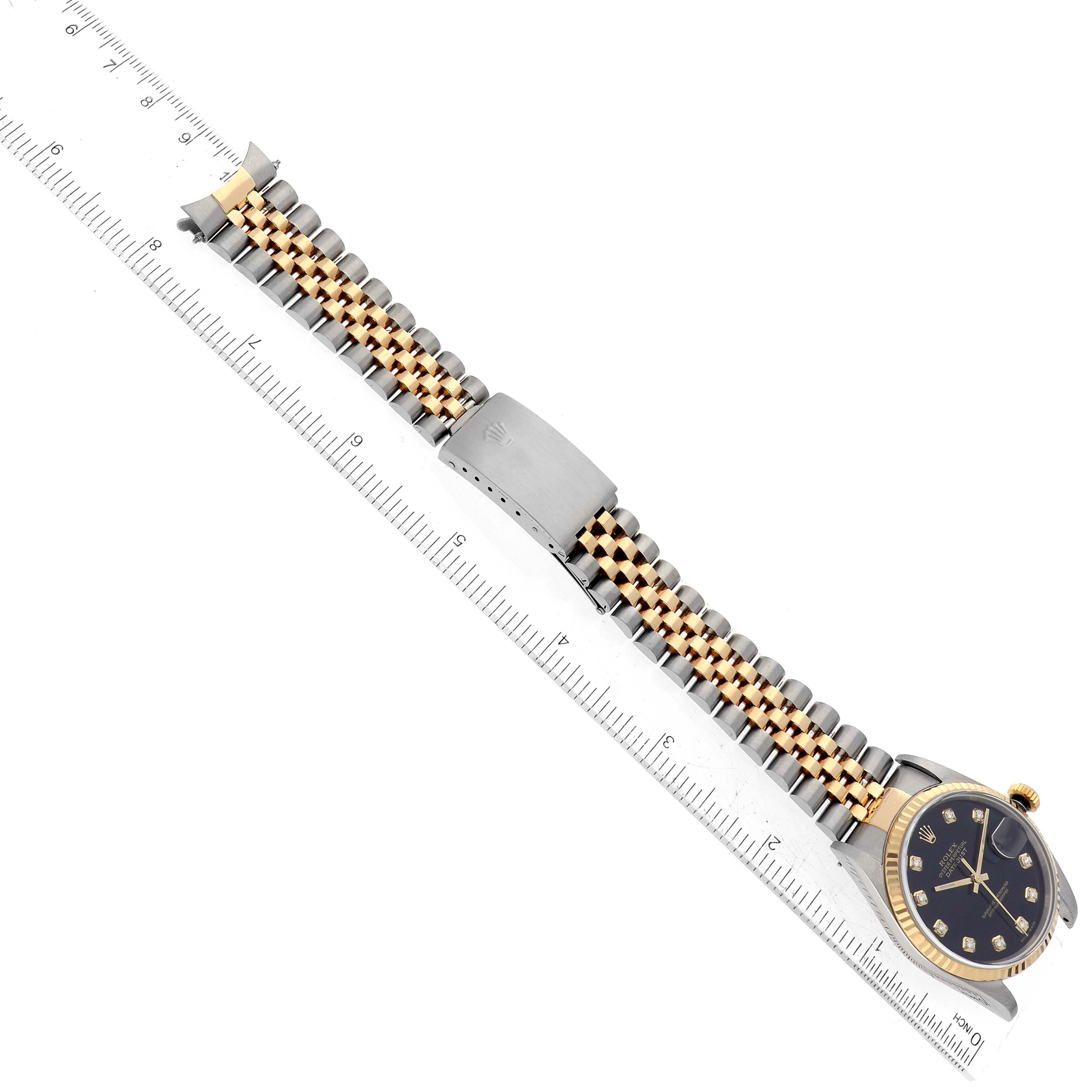 The image shows a Rolex Datejust 16233 Men's Steel and Gold (two tone) Black Dial 16233 Men's Steel and Gold (two tone) Black Dial watch laid flat, displaying the bracelet, clasp, case, and dial from a top-down angle beside a ruler.
