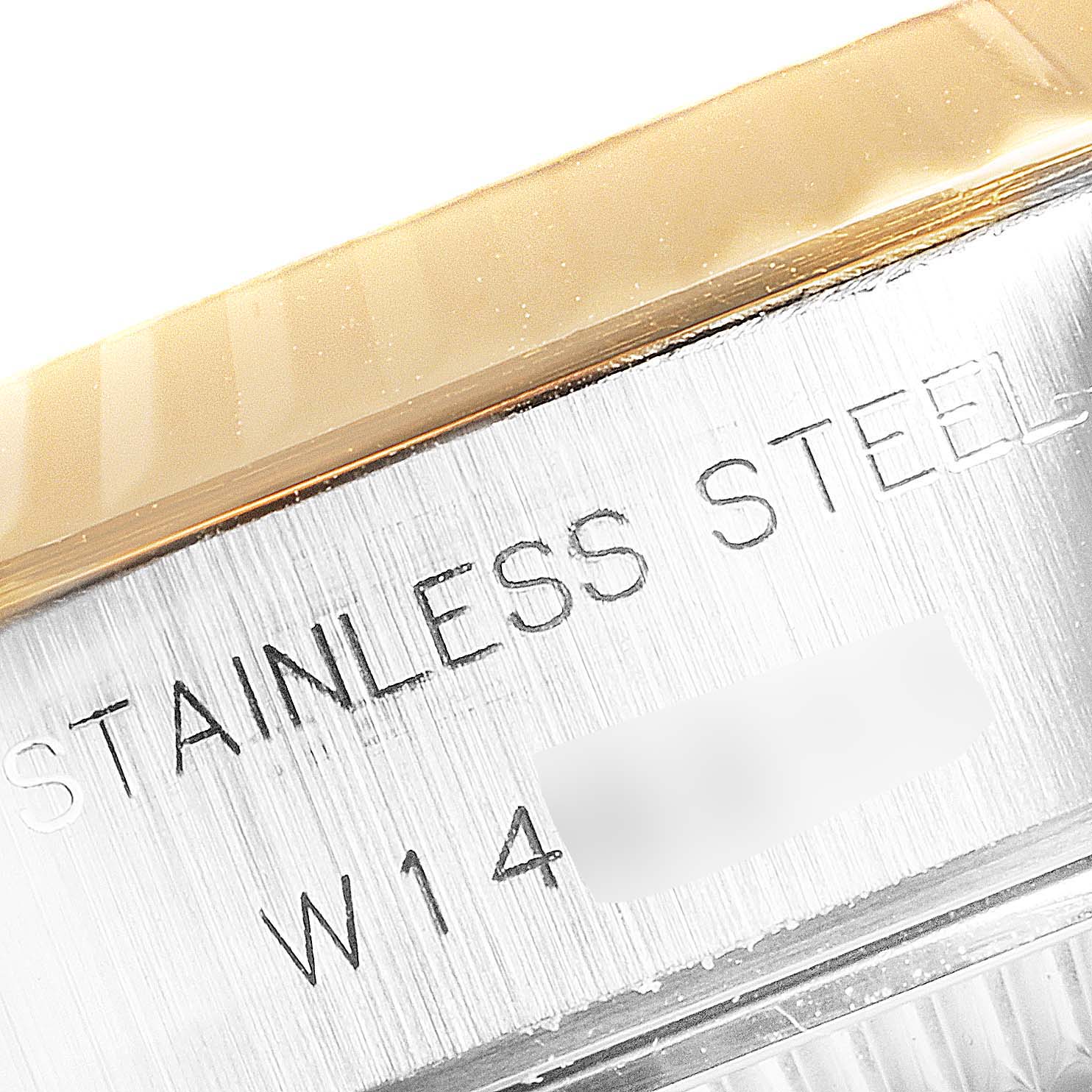 The image shows a close-up of the side of a Rolex Datejust 69173 Women
s Steel and Gold (two tone) Champagne Dial 69173 Women
s Steel and Gold (two tone) Champagne Dial watch, highlighting the stainless steel case and part of the gold bezel.