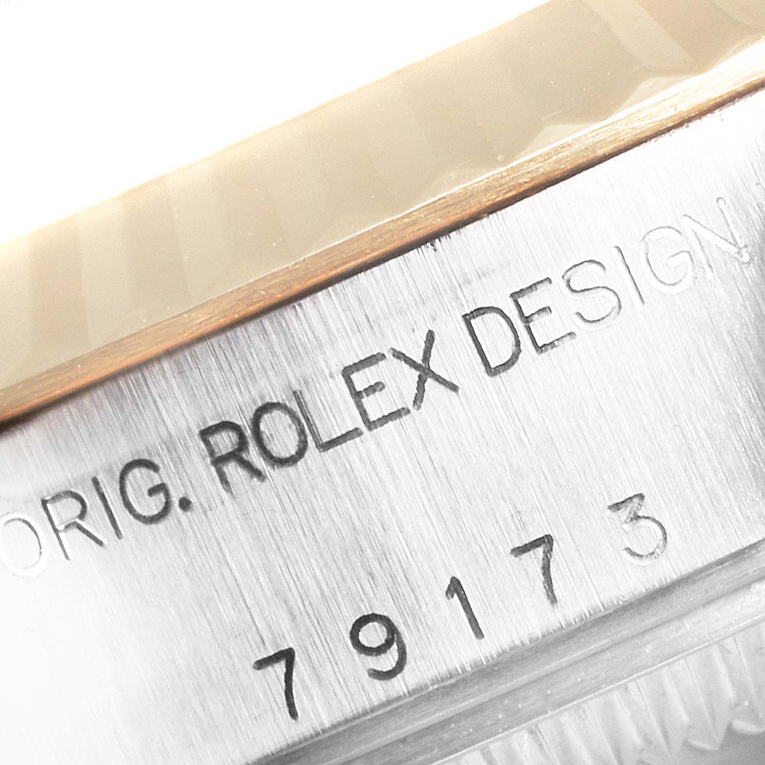 This close-up image shows the engraved serial number and “ROLEX DESIGN” text on the side of a Rolex Datejust 79173 Women
s Steel and Gold (two tone) White Dial 79173 Women
s Steel and Gold (two tone) White Dial watch.