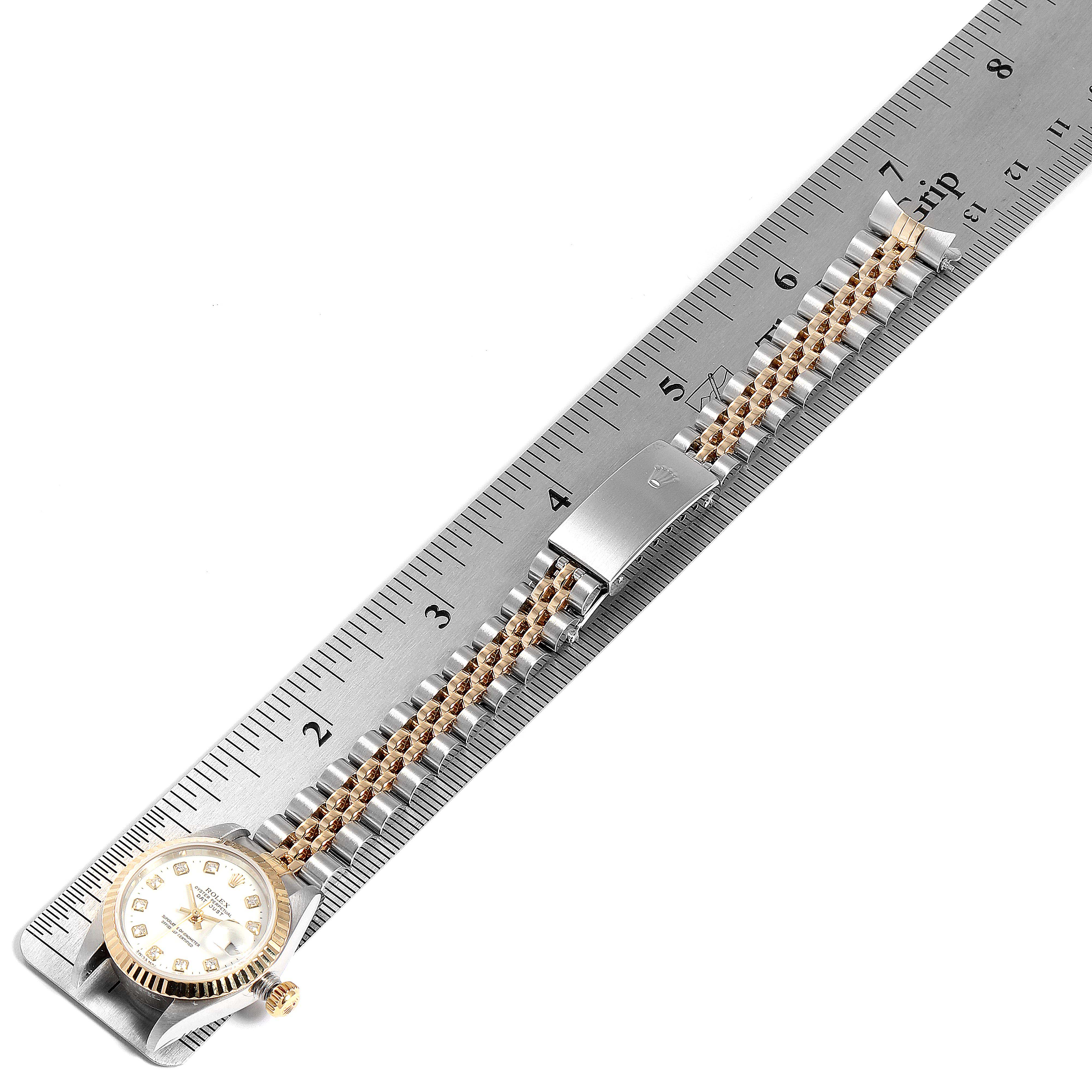 The Rolex Datejust 79173 Women
s Steel and Gold (two tone) White Dial 79173 Women
s Steel and Gold (two tone) White Dial watch is shown from a top-down angle alongside a measuring ruler, highlighting the face and band.